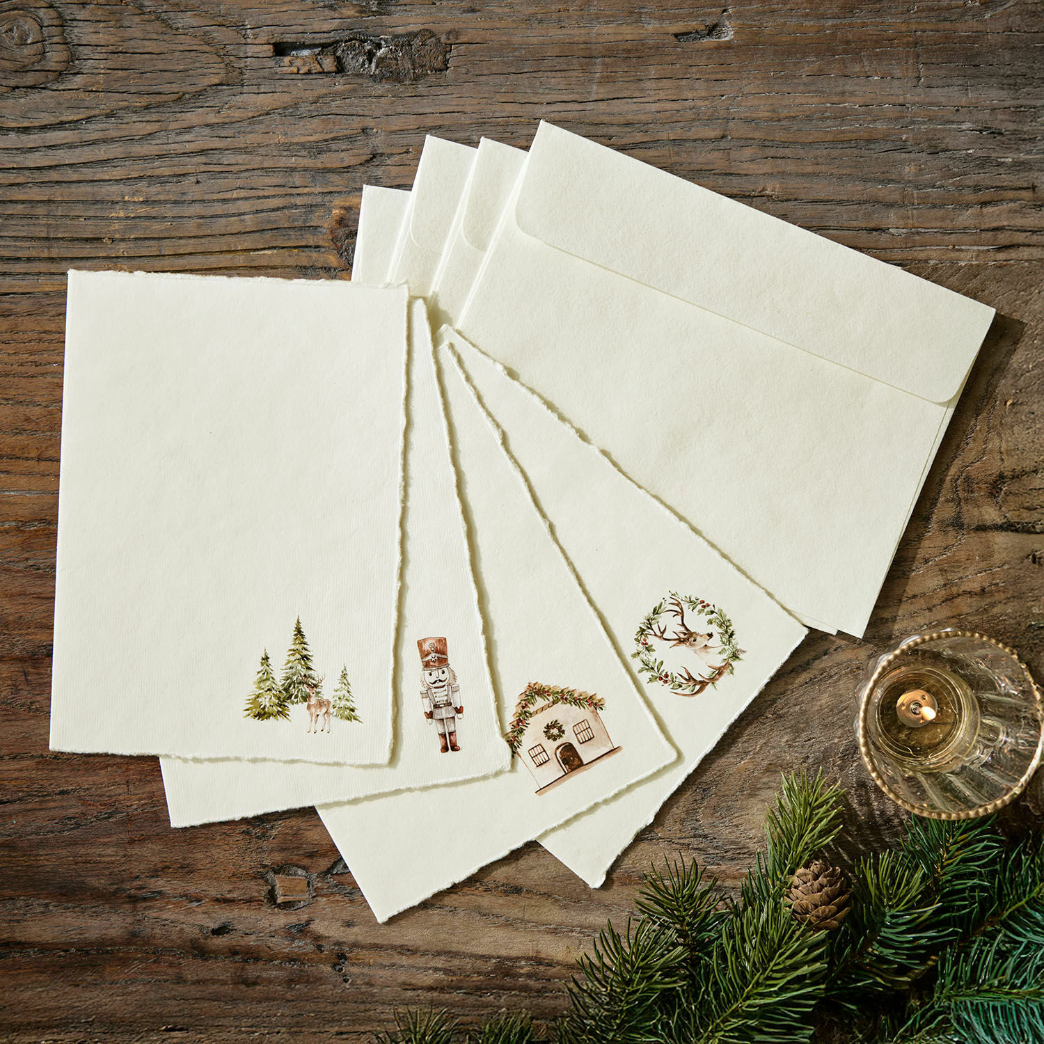 Wenskaart set van 4 Lorandis Set crèmekleurige kaarten en enveloppen met kerstmotieven op houten tafel met dennentakken