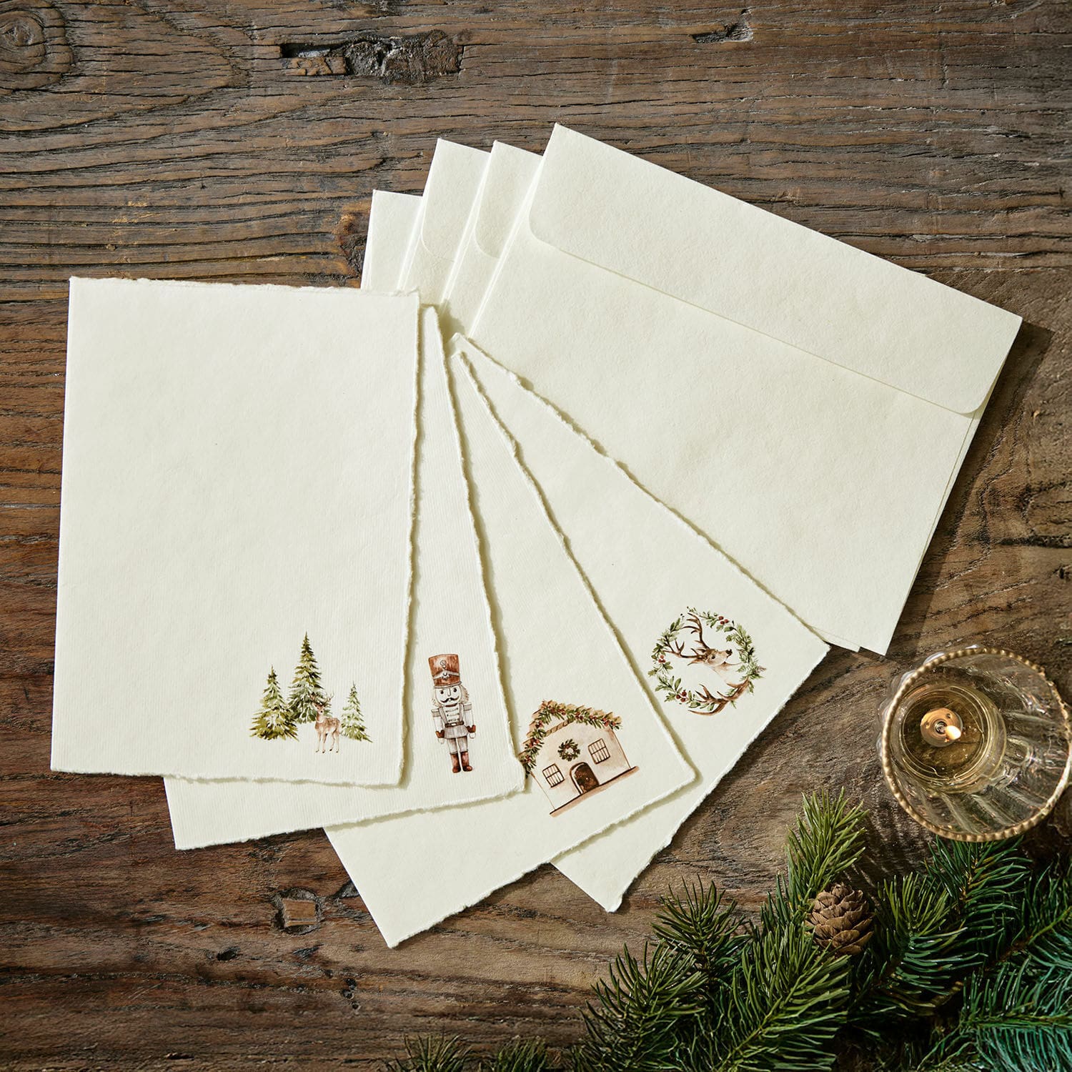 Wenskaart set van 4 Lorandis Set crèmekleurige kaarten en enveloppen met kerstmotieven op houten tafel met dennentakken