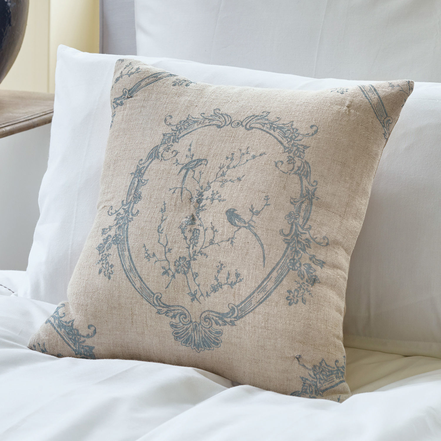 Kussenhoes Decadence Beige linnen kussen met blauw patroon van vogels en bloemen op wit beddengoed, slaapkamerdecoratie