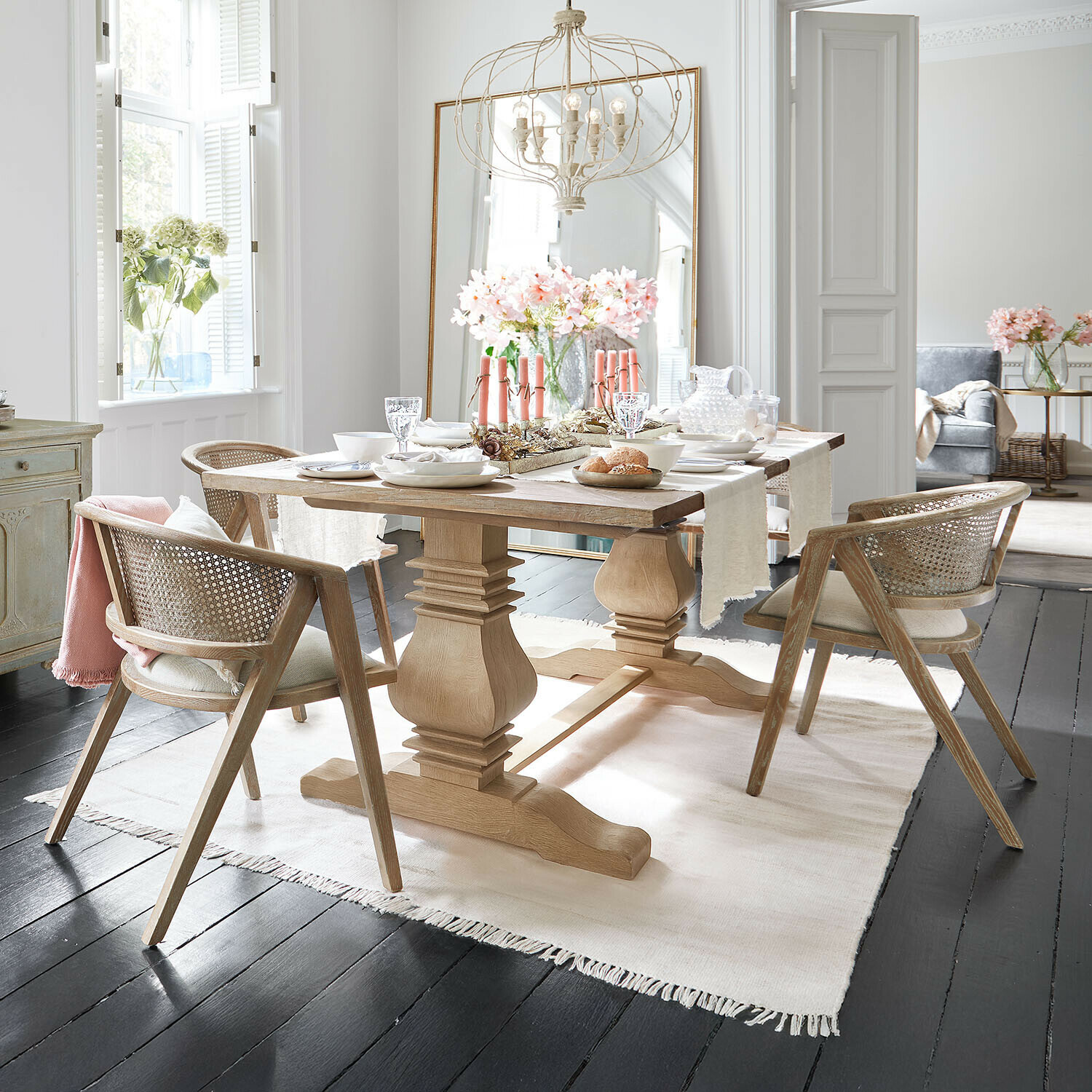 Lichte houten eettafel met rotan stoelen en tafeldecoratie in moderne eetkamer