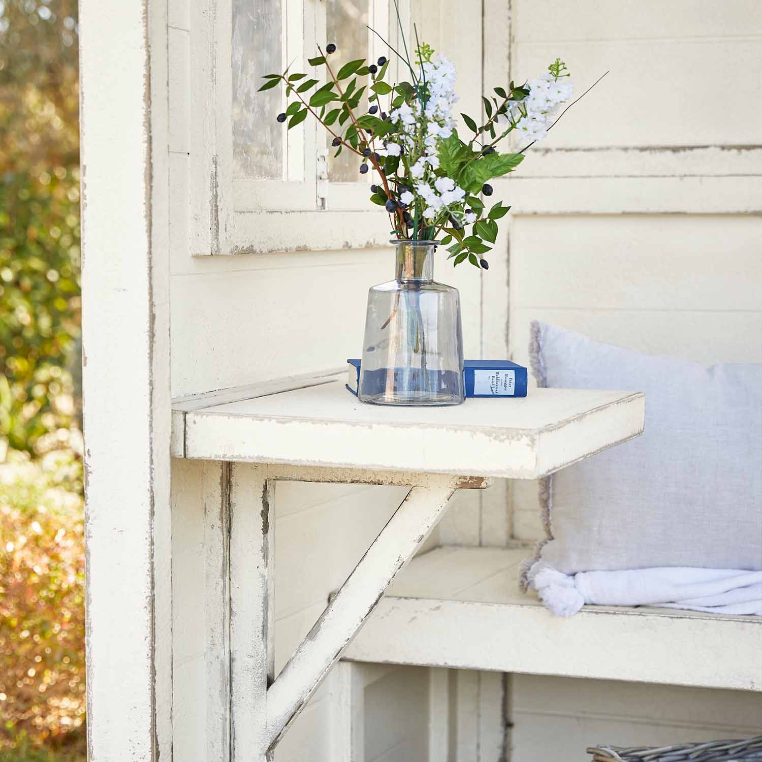 Witte inklapbare houten tafel met doorzichtige vaas en bloemen, tuindecoratie