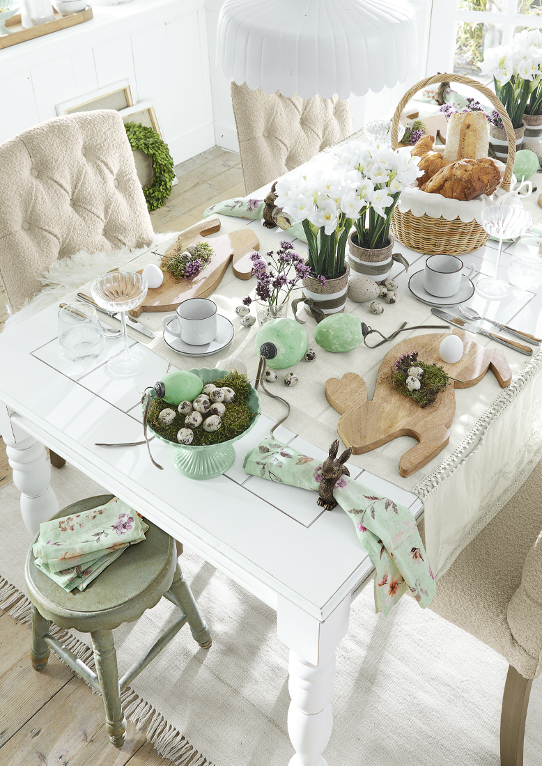 Lichte rustieke eettafel met paasdecoratie en witte bloemen in lichte kamer