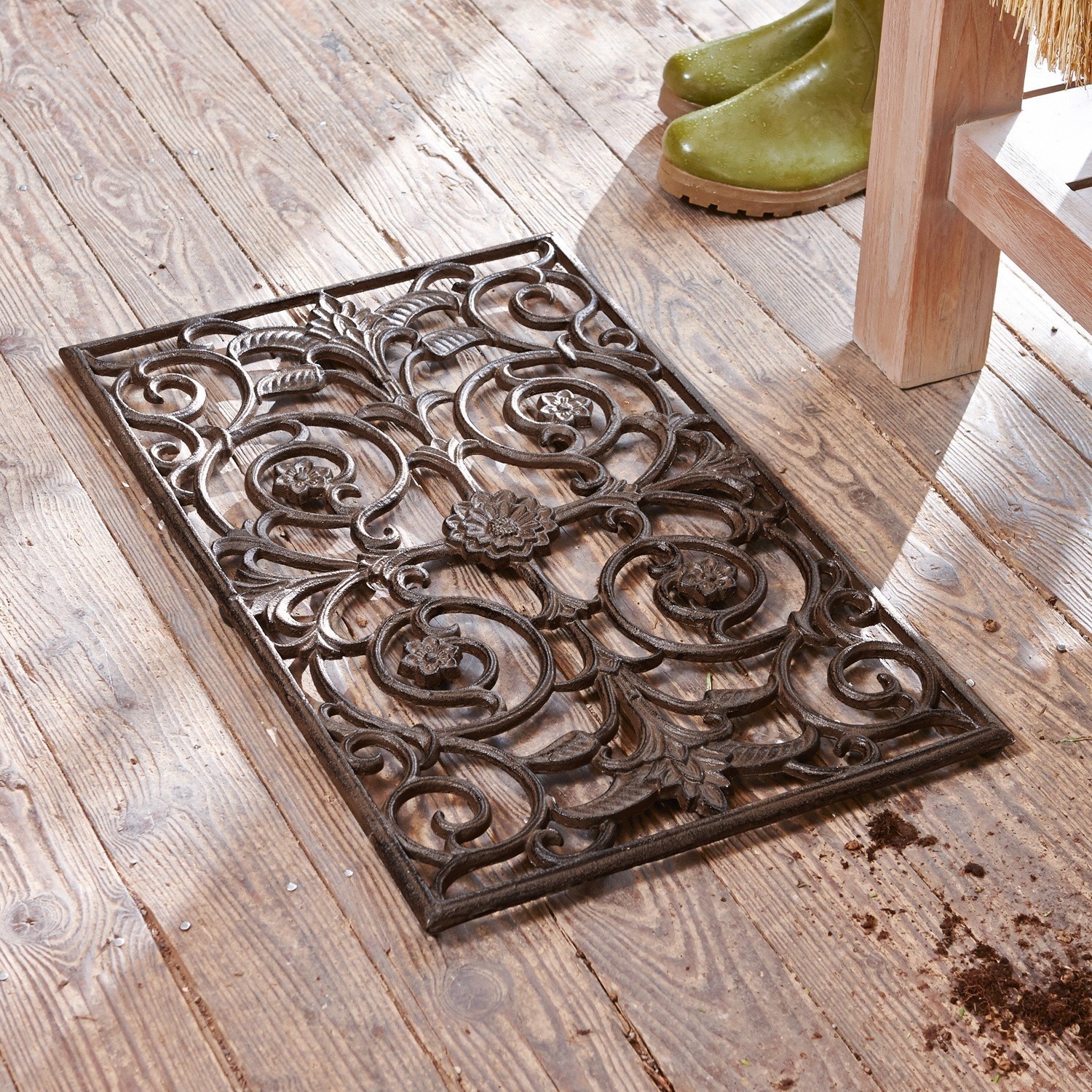 Decoratieve ijzeren mat met bloemmotief op houten vloer, decoratieve deurmat