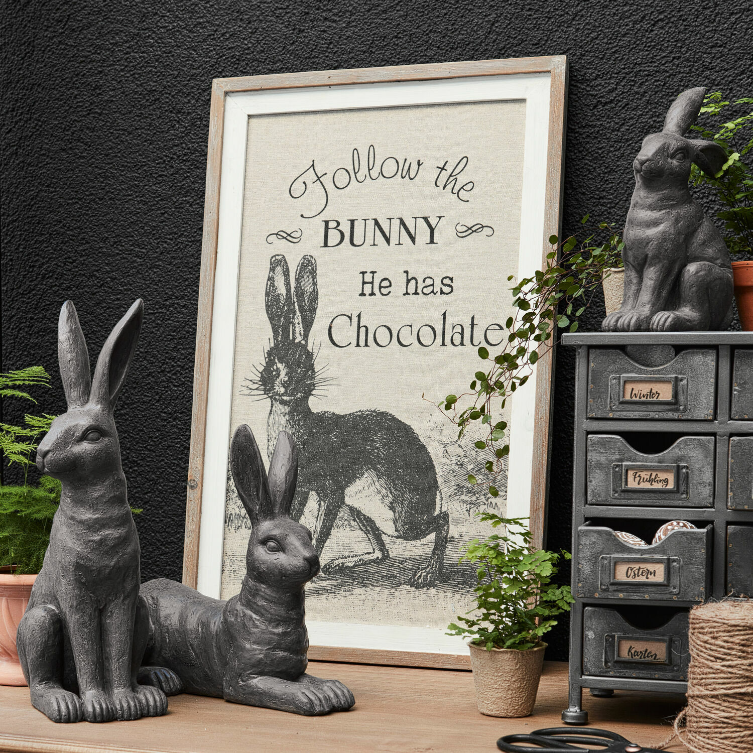Decoboard Chocolate Grijze decoratieve konijnenfiguren met lijst en tekst over konijn en chocolade op houten tafel