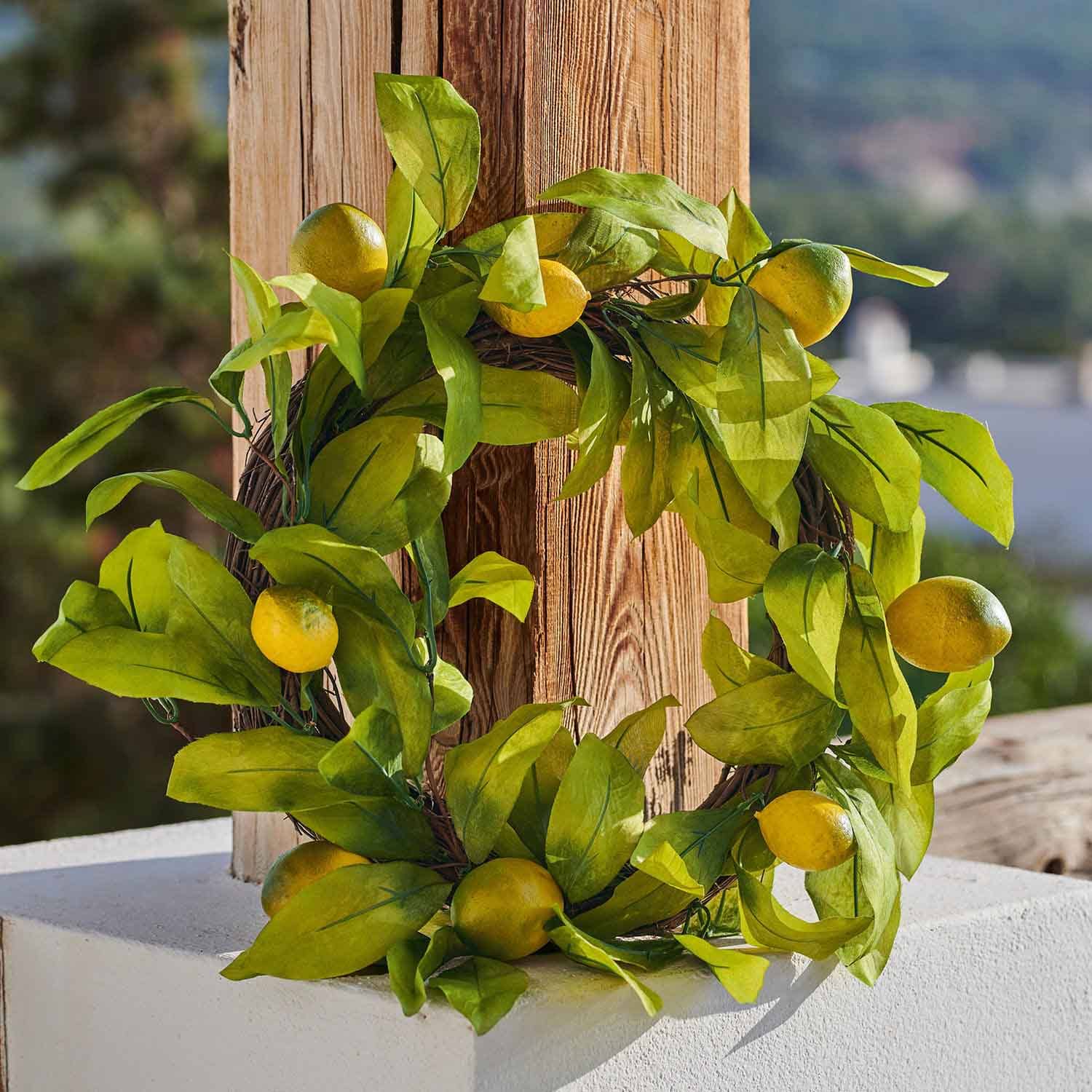 Decoratieve krans met gele citroenen en groene bladeren tegen houten achtergrond, zomerse decoratie