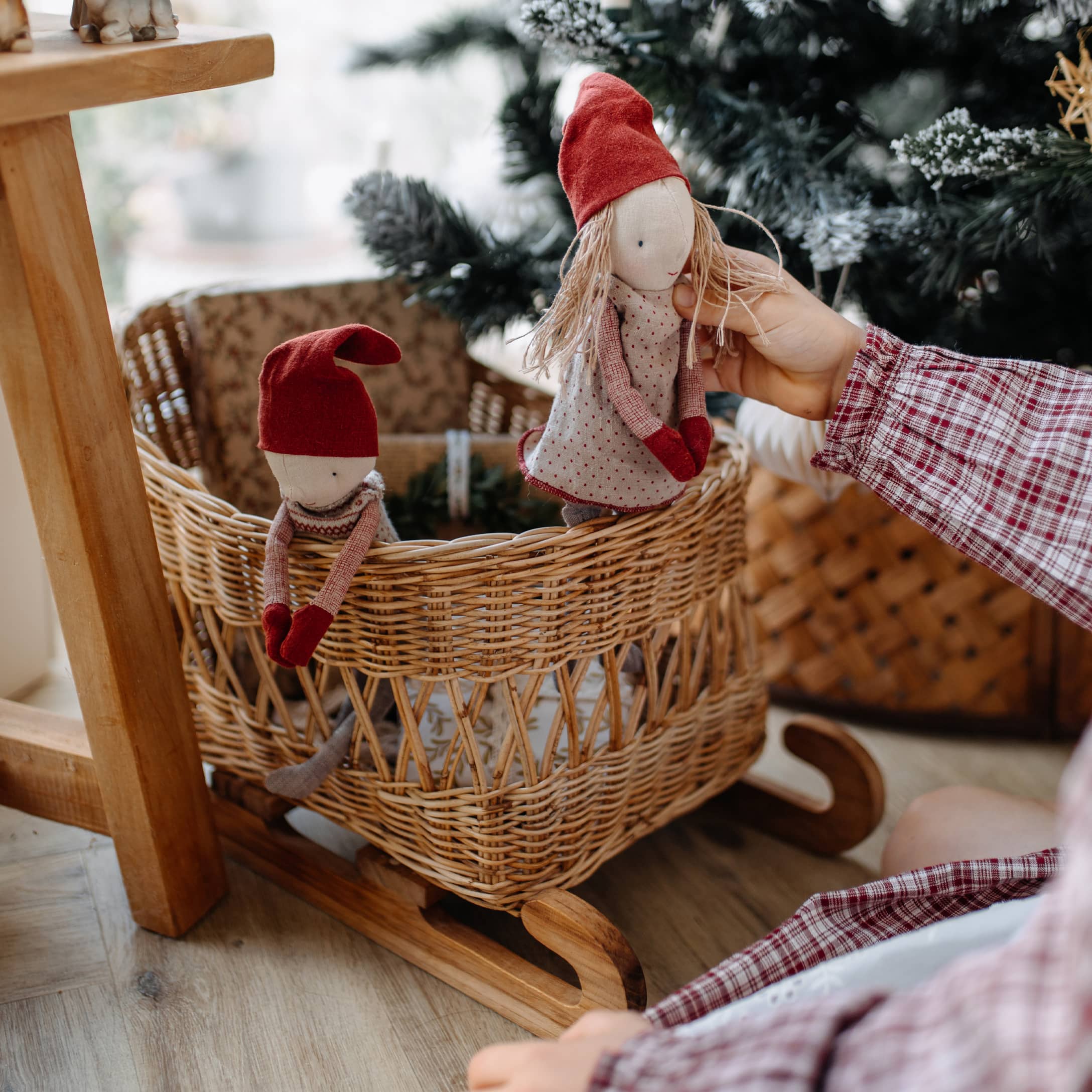 Houten schommelwieg met rieten mand en twee poppen met rode mutsen, kerstdecoratie