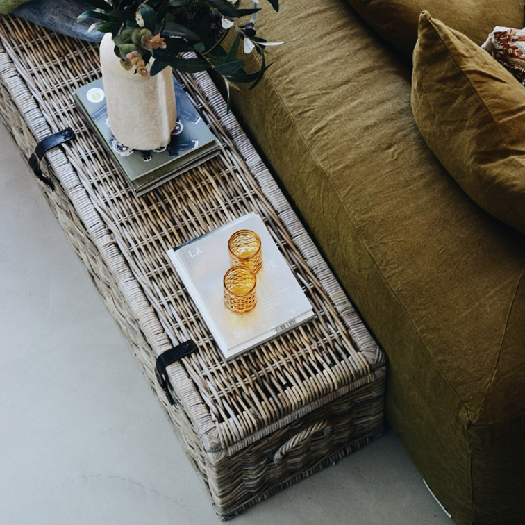 Rieten salontafel in natuurlijke kleur met decoratie en groene bank ernaast, Scandinavische stijl