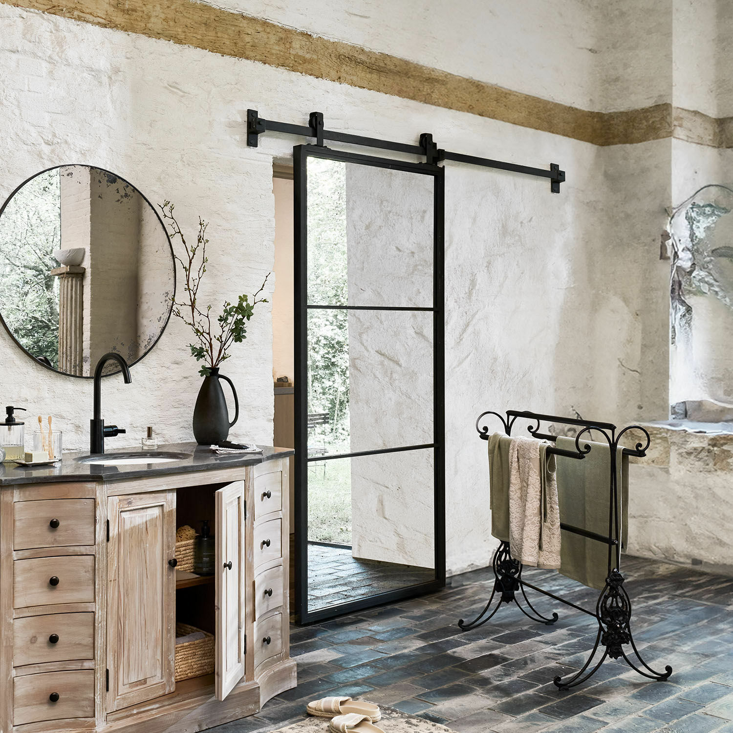 Rustieke badkamer met houten kast, zwarte metalen handdoekhouder en glazen schuifdeur