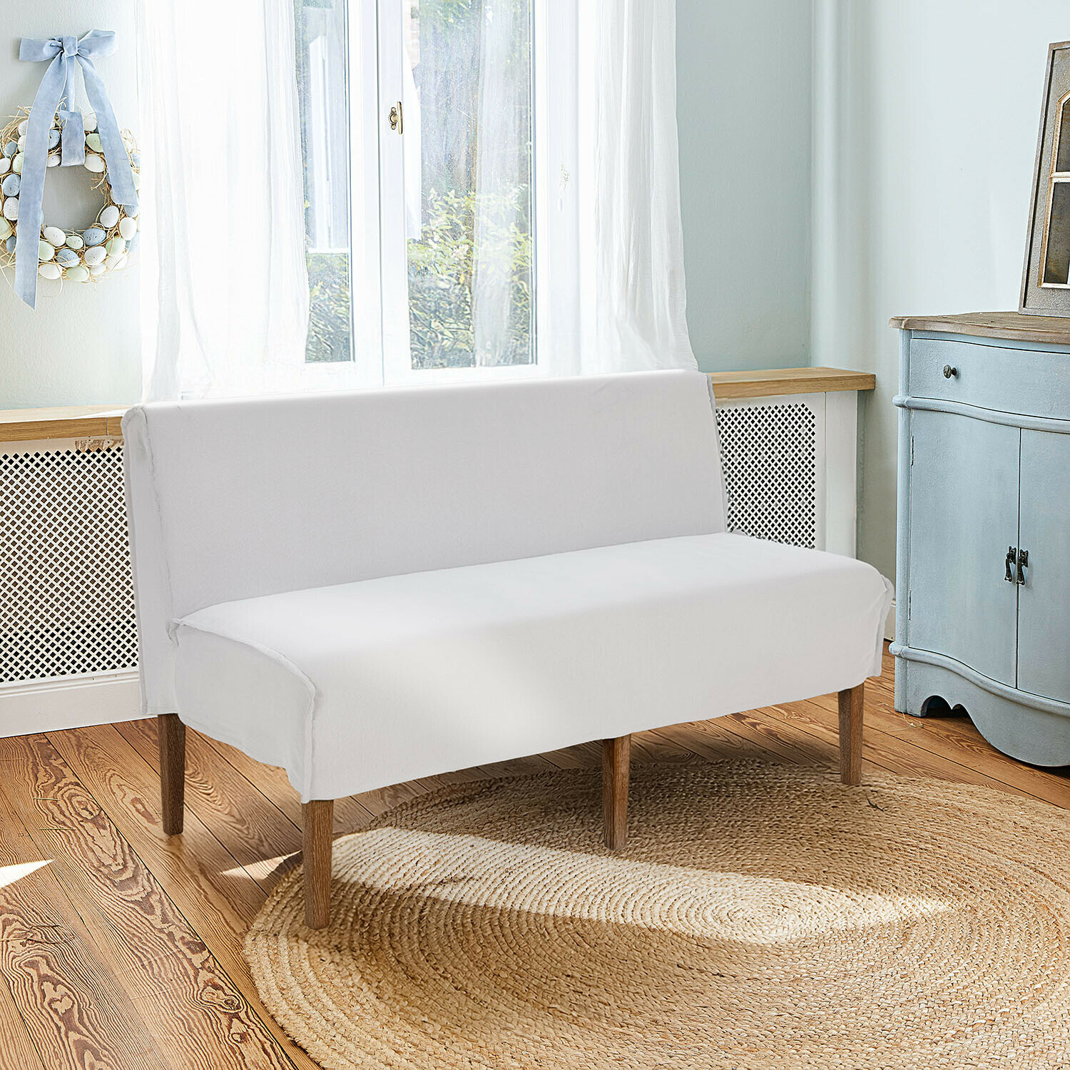 Witte bank met houten poten op ronde jute vloerkleed in lichte, gezellige kamer