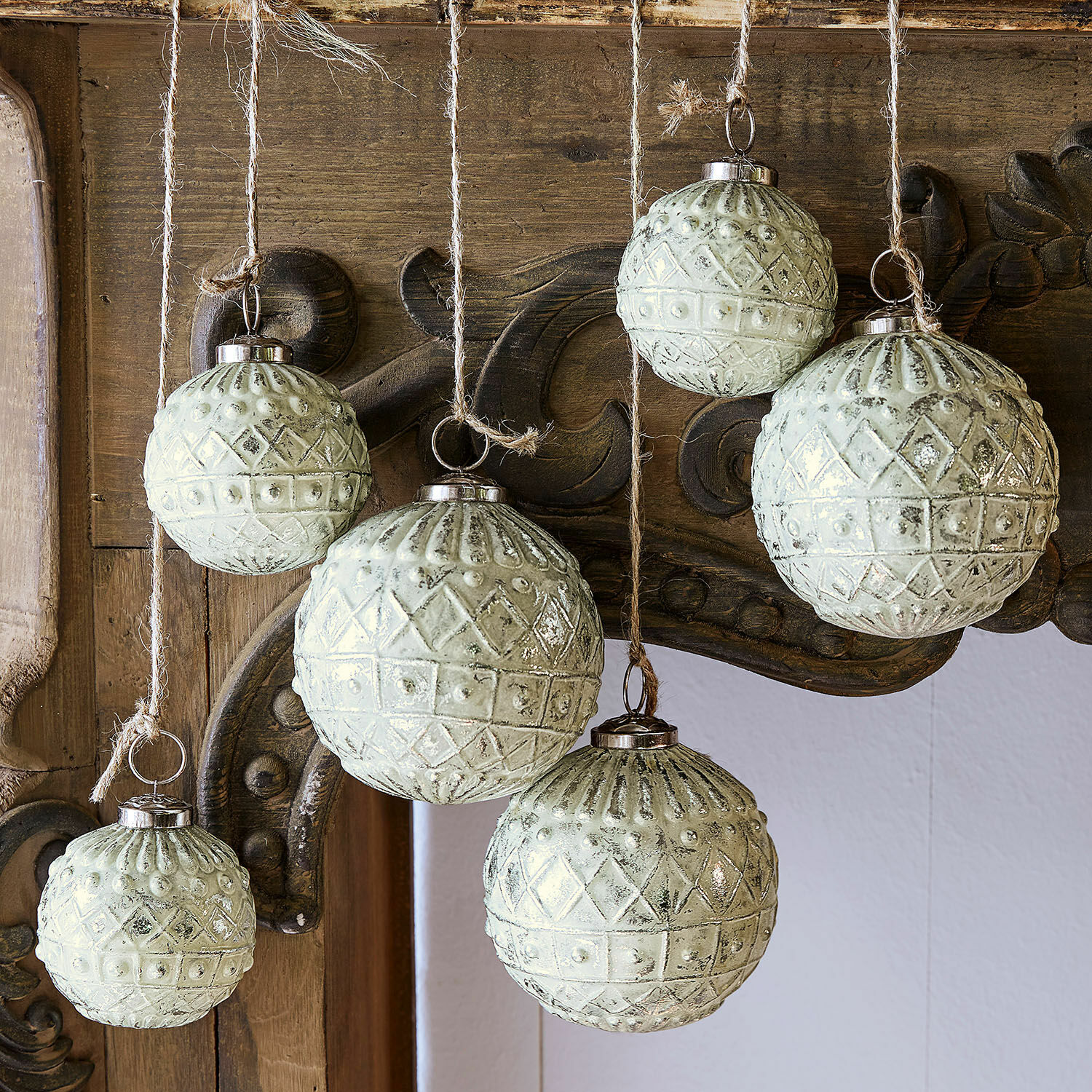 Set van zes groenachtige glazen kerstballen met patroon, hangend aan touwtjes