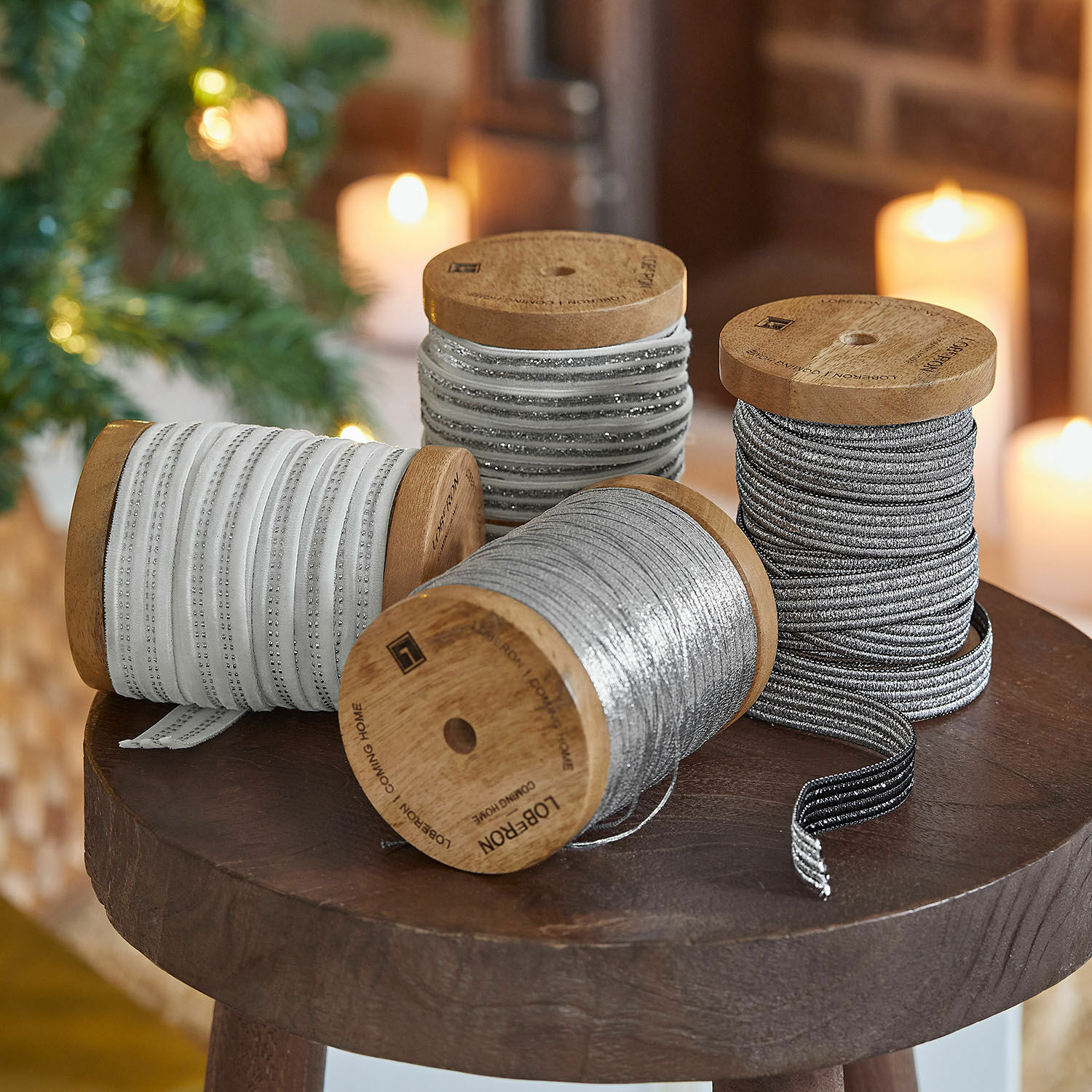 Lint set van 4 Arceno Houten spoelen met decoratieve witte en zilveren linten op een houten tafel