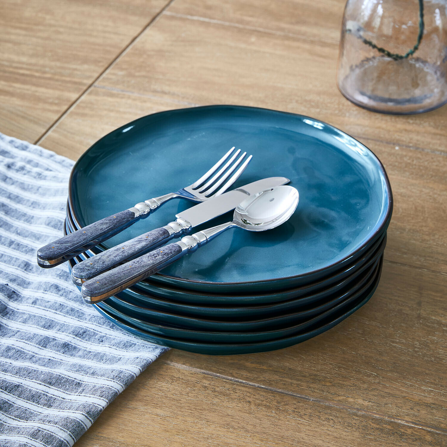 Set blauwe keramische borden met metalen bestek met houten handvatten op houten tafel