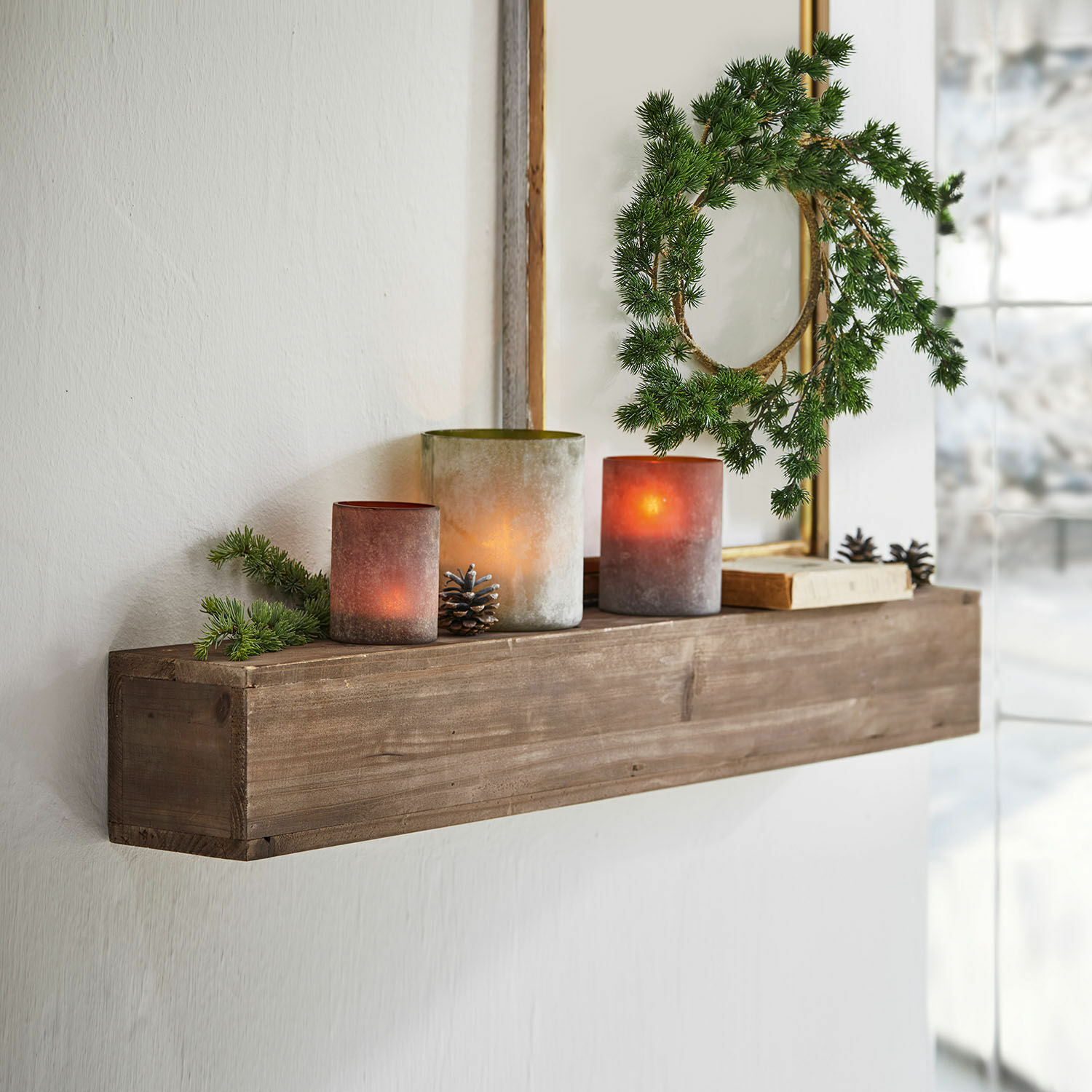 Wandplank Visayas Houten wandplank met decoratieve kaarsen en groene krans in lichte kamer