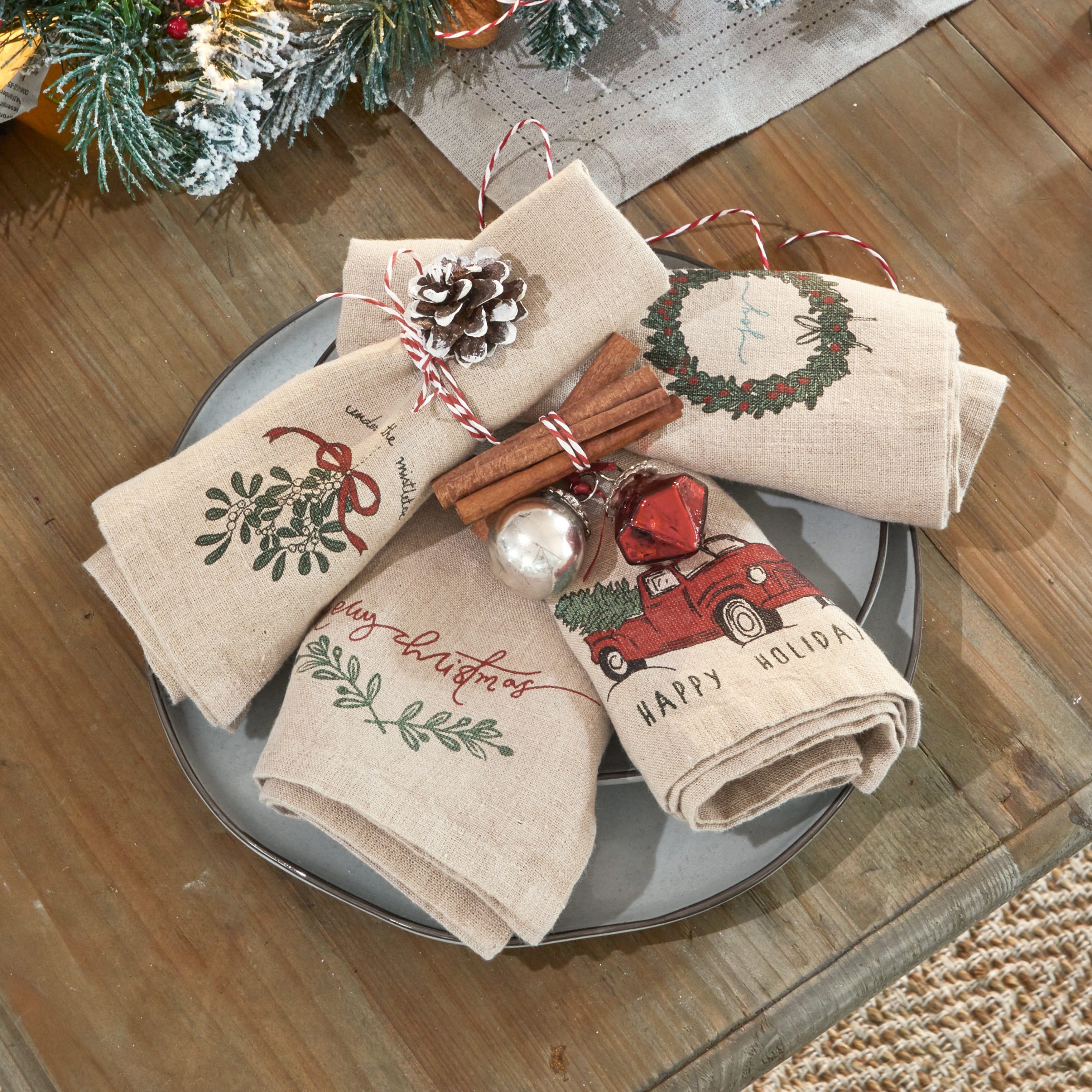 Linnen servetten met kerstmotieven, versierd met kaneelstokjes en dennenappel op grijze schaal