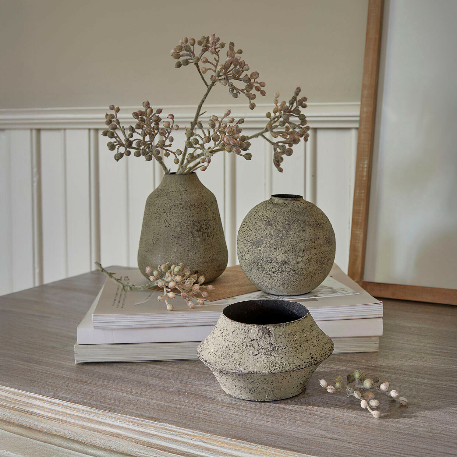 Drie decoratieve beige steengoed vazen op houten tafel met gedroogde takken