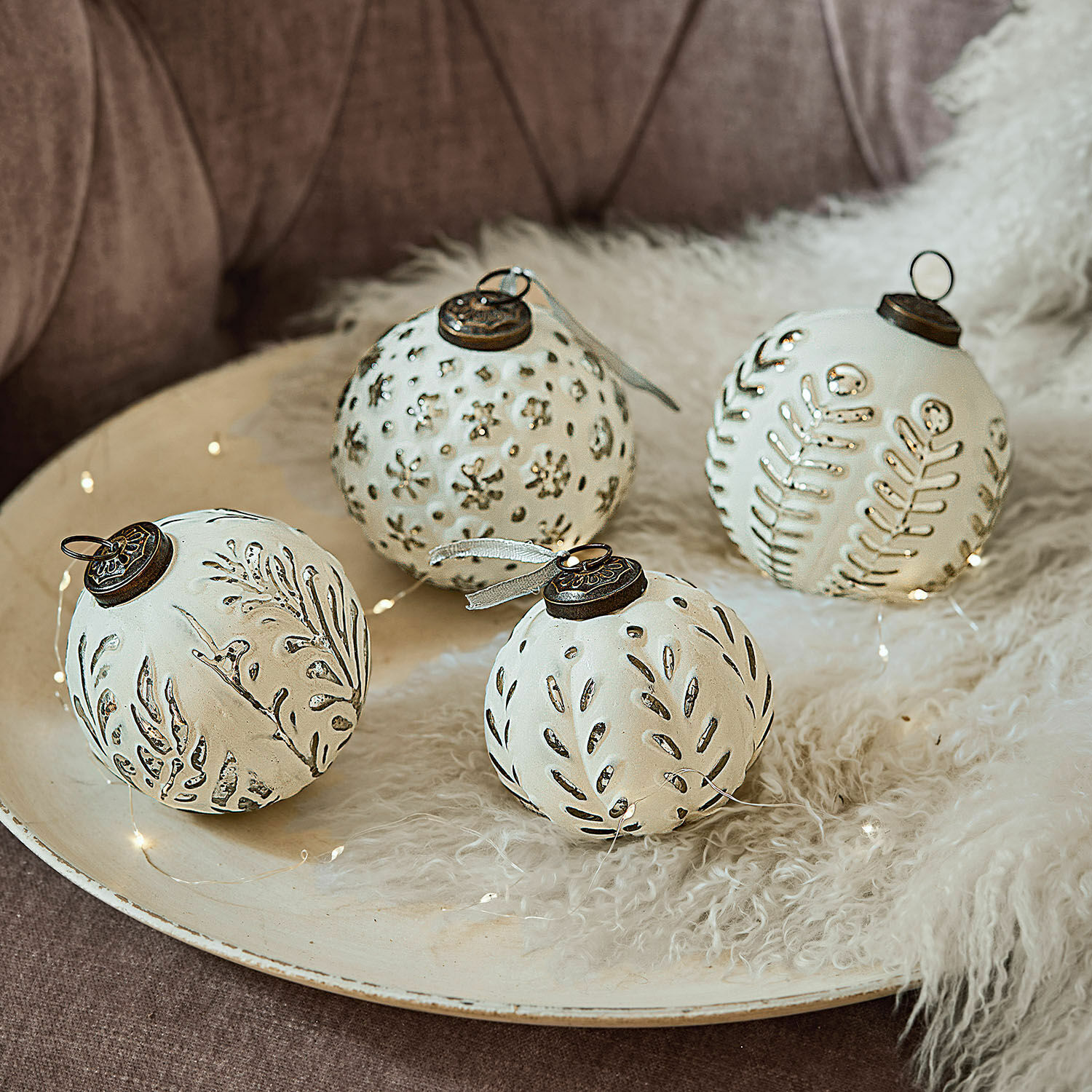 Set van vier witte keramische kerstballen met plantenpatronen en metalen ophangingen