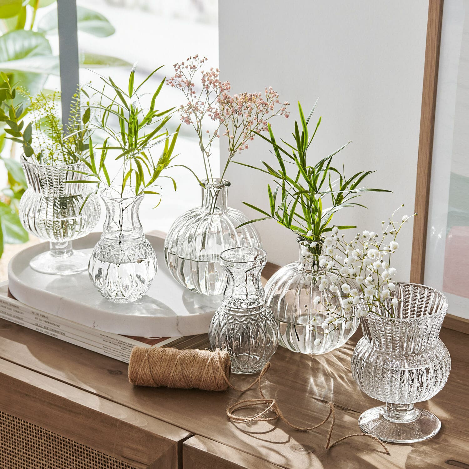 Vaas set van 6 Amber Set transparante glazen vazen met groene en witte bloemen op houten kast