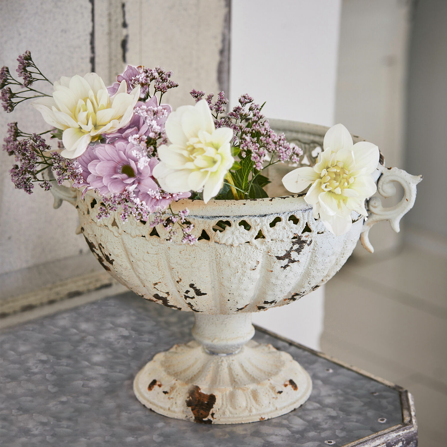 Witte metalen schaal met verweerde look en pastelkleurige bloemen op decoratieve tafel