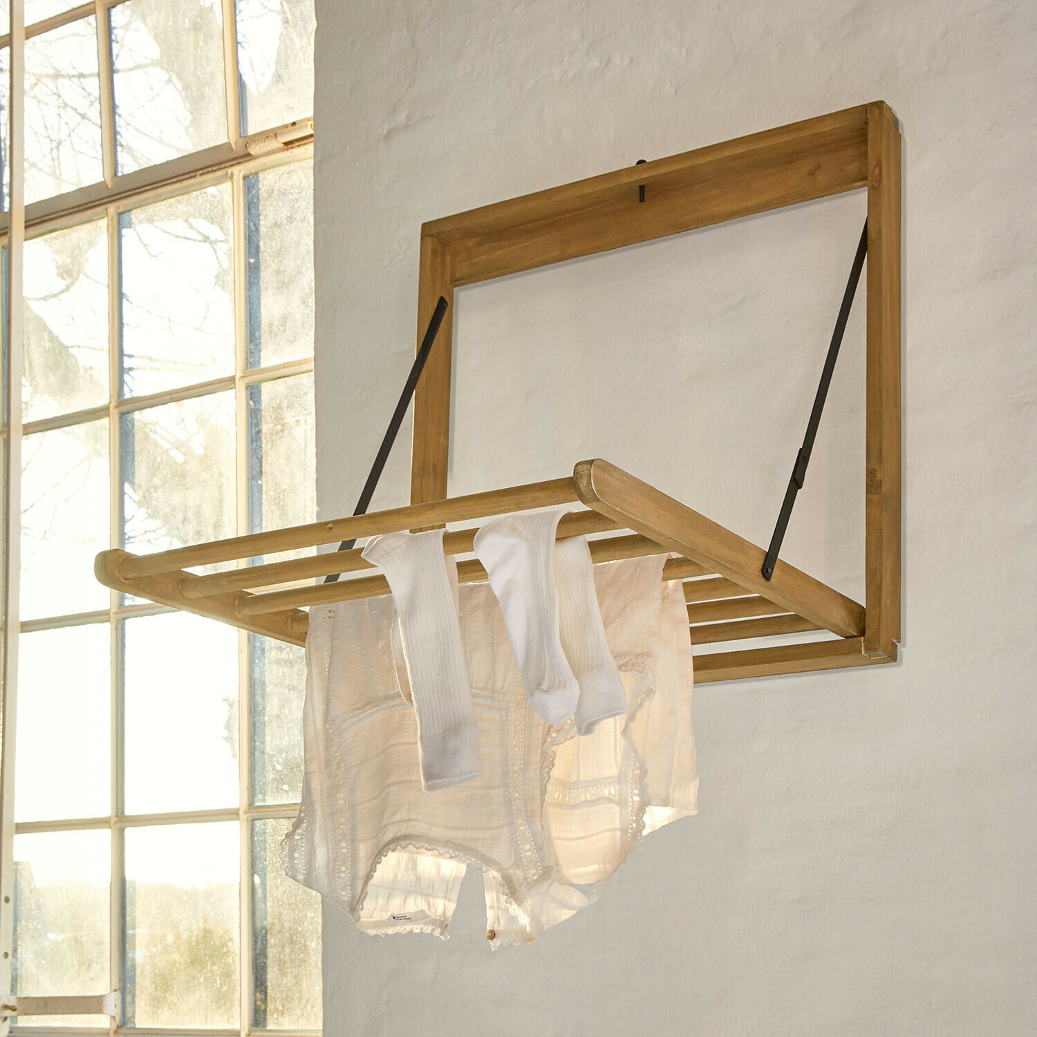 Wanddroogrek Élirème Opklapbare houten wanddroger in lichte houtkleur met witte kleding in lichte kamer