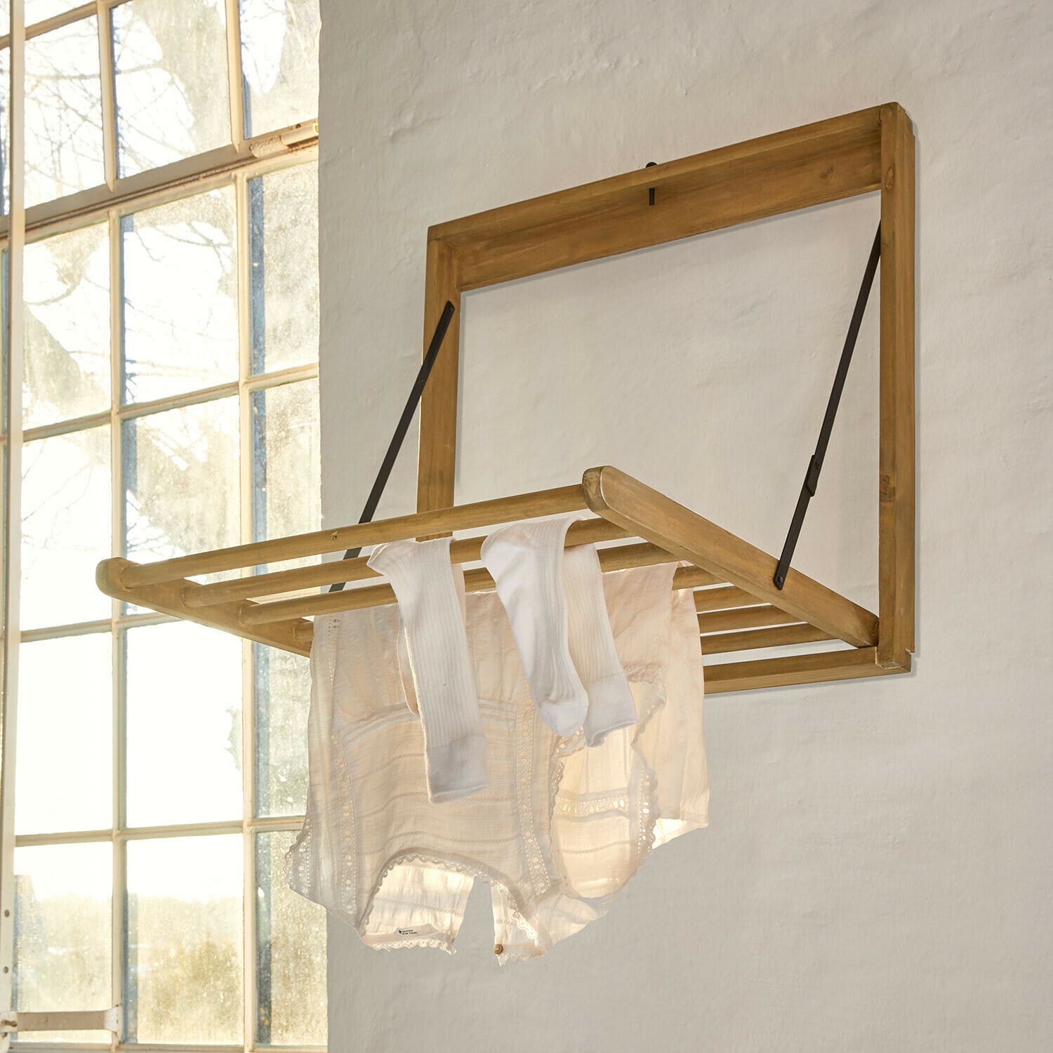Wanddroogrek Élirème Opklapbare houten wanddroger in lichte houtkleur met witte kleding in lichte kamer