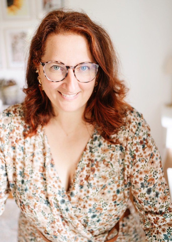 Vrouw met bril en bloemenblouse in een warme, huiselijke omgeving