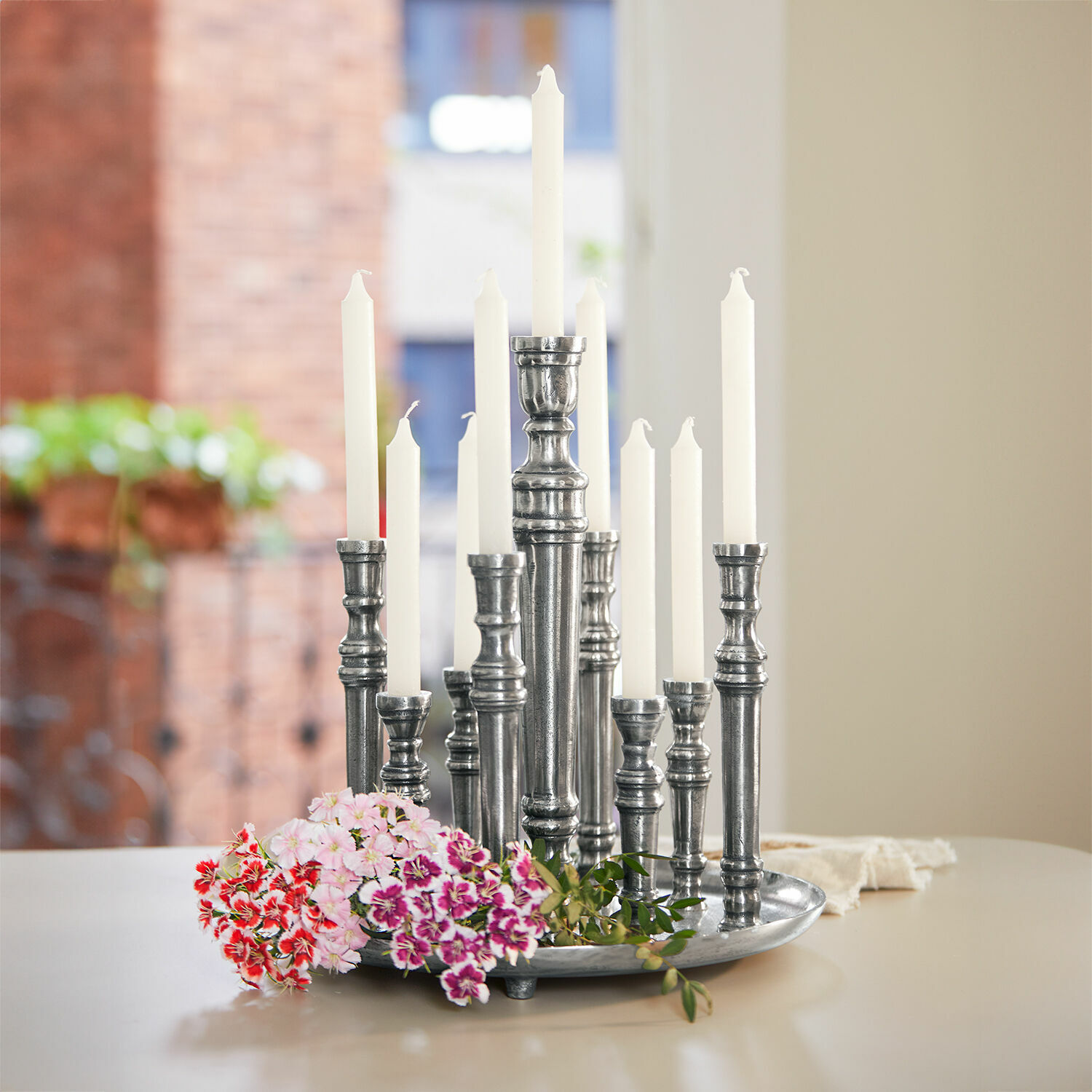 Kaarsenhouder Calcot Metalen kandelaar met witte kaarsen en kleurrijke bloemen op tafel in lichte kamer
