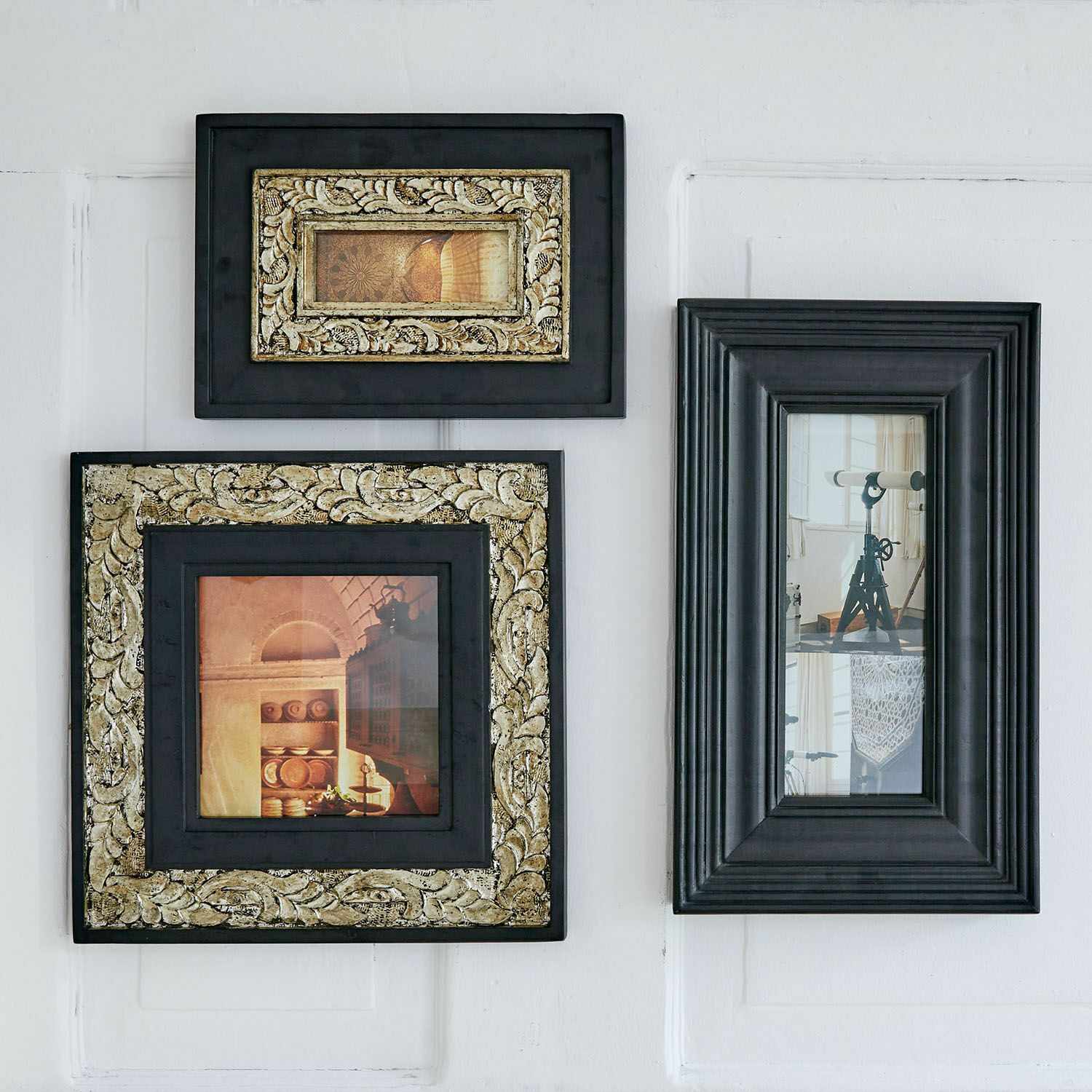 Set van drie zwarte houten lijsten met gouden versieringen en decoratieve foto's aan de muur