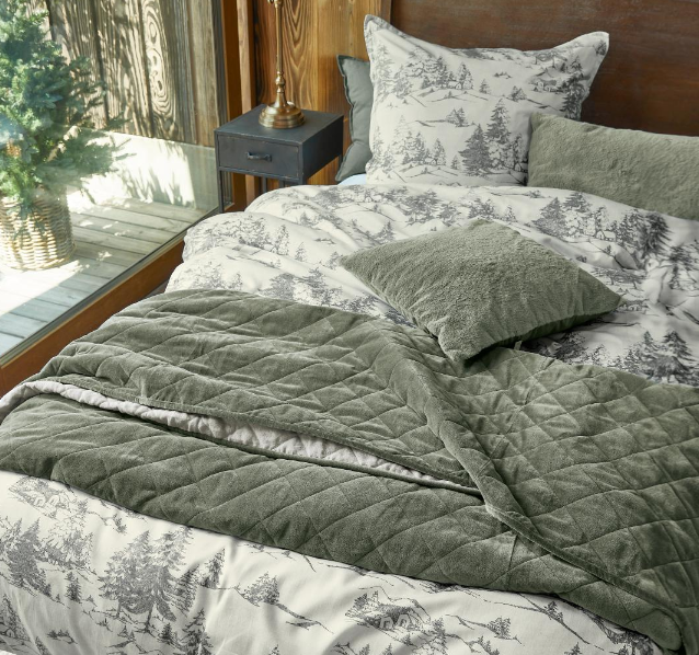 Groene fluwelen plaid op bed met beddengoed met bosmotief, zachte en decoratieve slaapkamertextiel