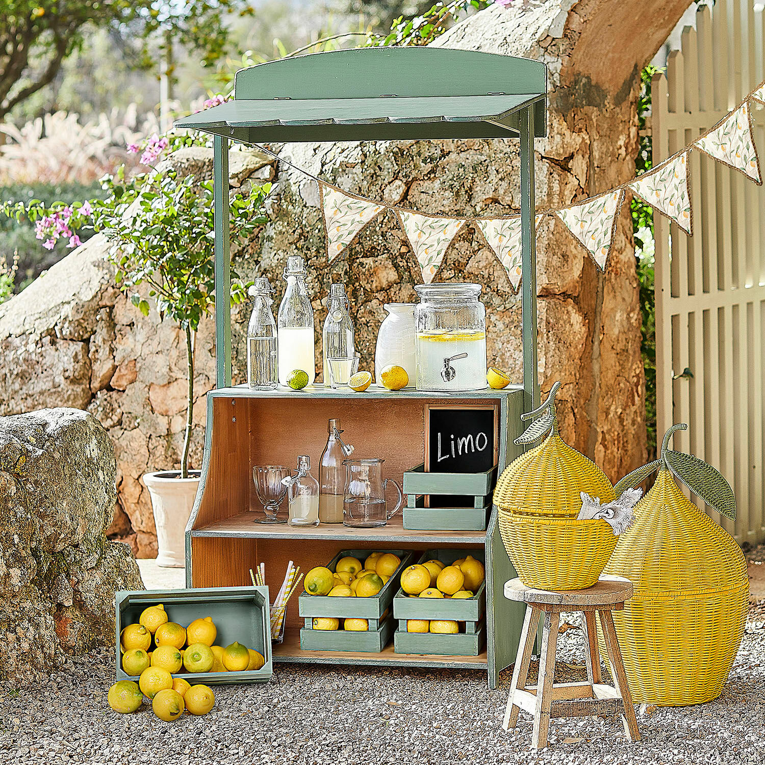 Limonadekraam Éclairon Groene houten stand met citroenen en glazen flessen voor limonade in de tuin