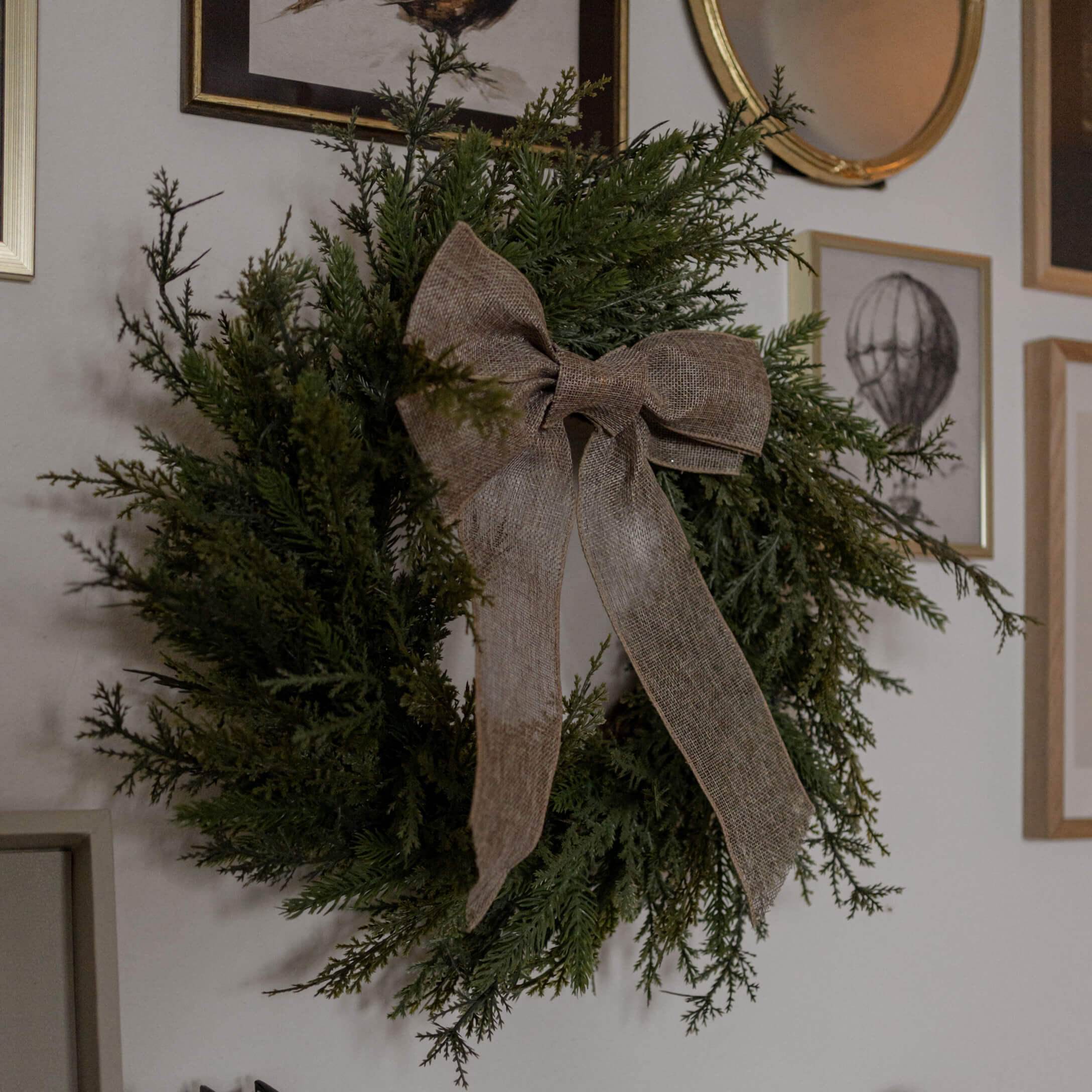 Decoratieve krans van groene takken met een bruine juten strik aan de muur in de woonkamer