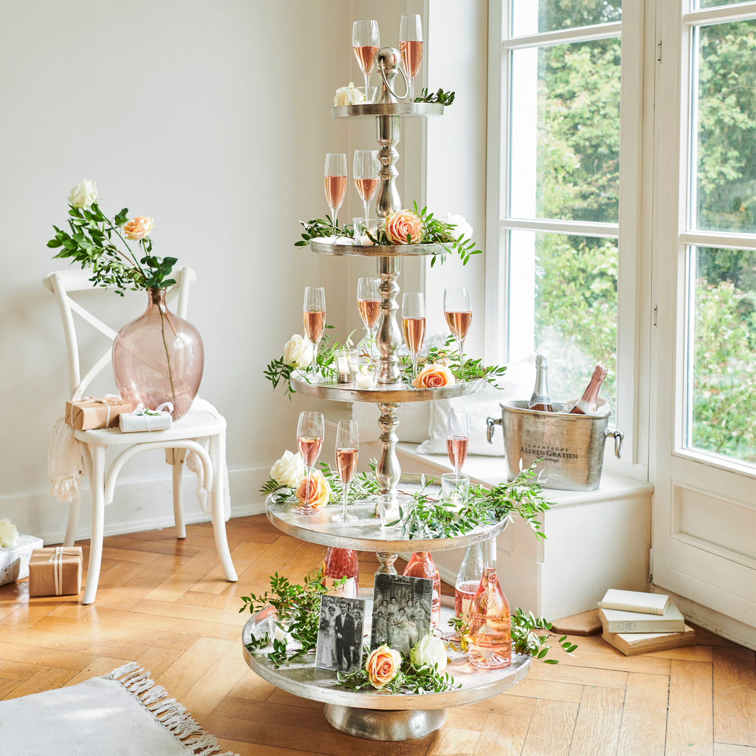 Vierlaagse metalen etagère met roséwijn en bloemdecoraties in lichte kamer