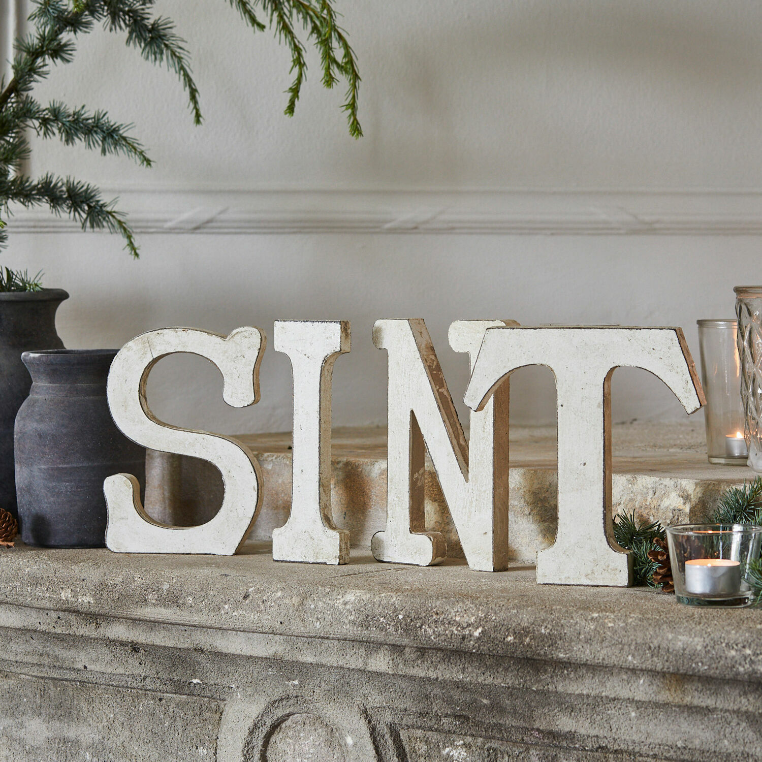 Decoratieletters Sint Witte houten decoratieve letters S I N T op een stenen schoorsteen met natuurlijke versieringen