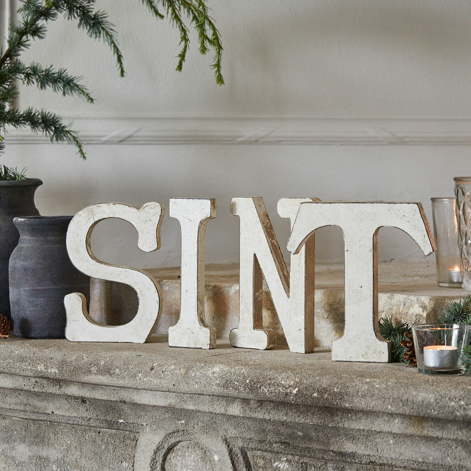 Decoratieletters Sint Witte houten decoratieve letters S I N T op een stenen schoorsteen met natuurlijke versieringen
