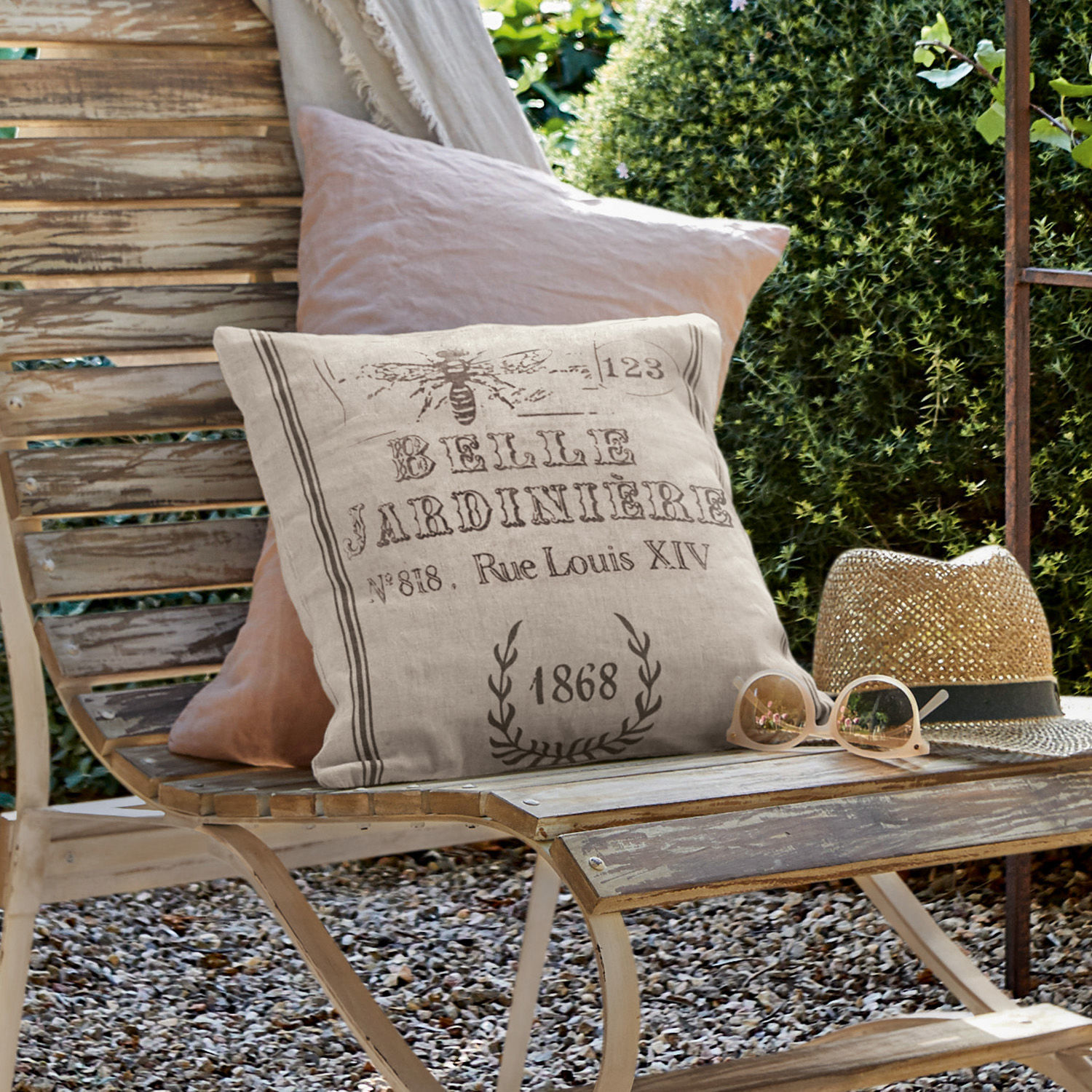 Kussenhoes Abelle Beige linnen sierkussen met vintage print op verweerde houten bank in tuin met hoed en bril