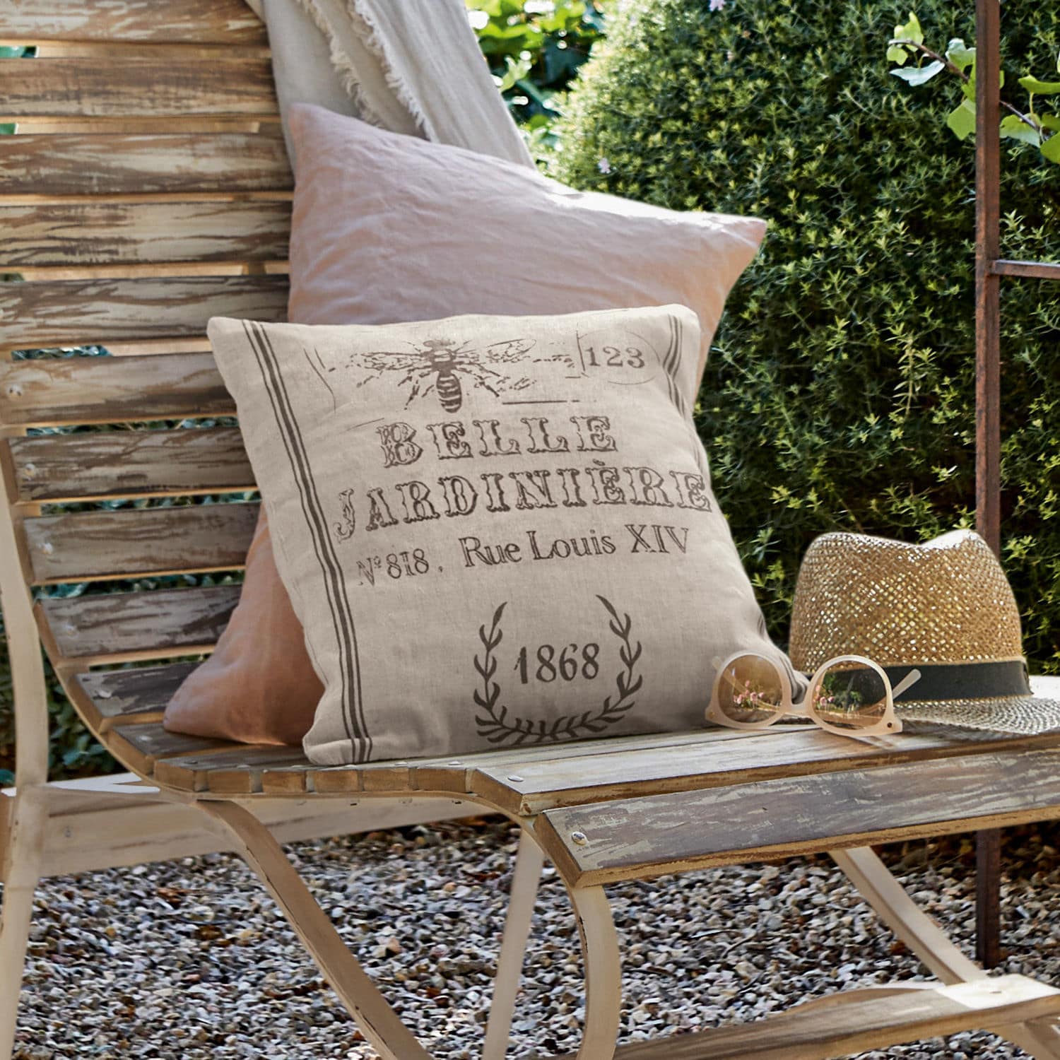 Kussenhoes Abelle Beige linnen sierkussen met vintage print op verweerde houten bank in tuin met hoed en bril