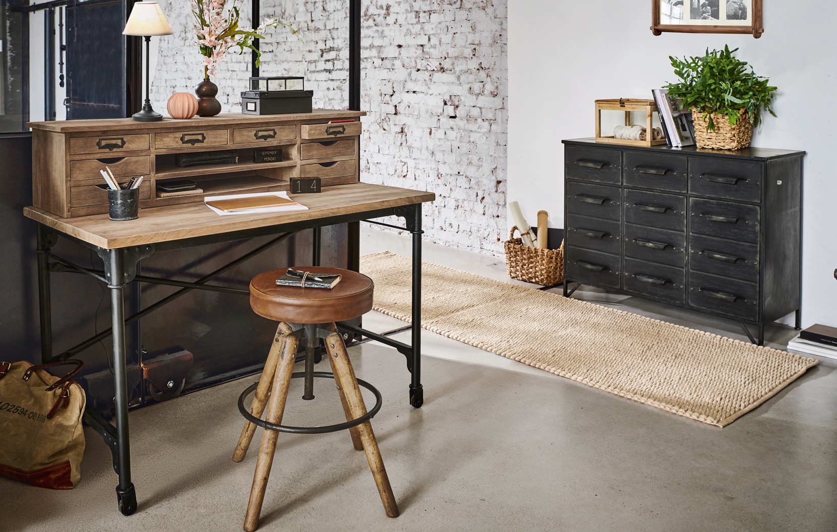 Industrieel bureau van hout en metaal met veel laden en vintage leren kruk in moderne kamer