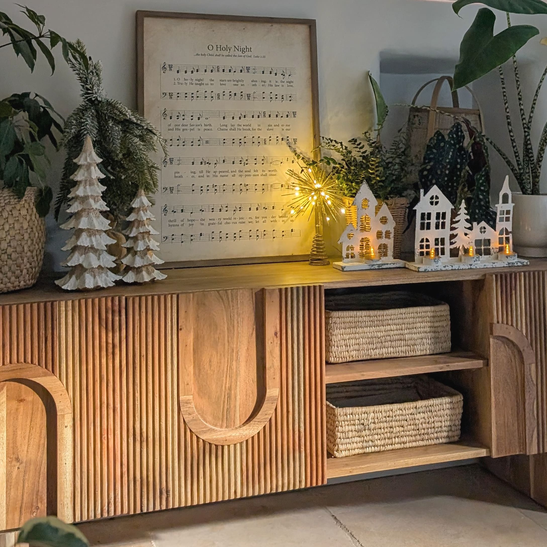 Houten dressoir met kerstdecoratie, witte huisjes en bomen met LED-verlichting