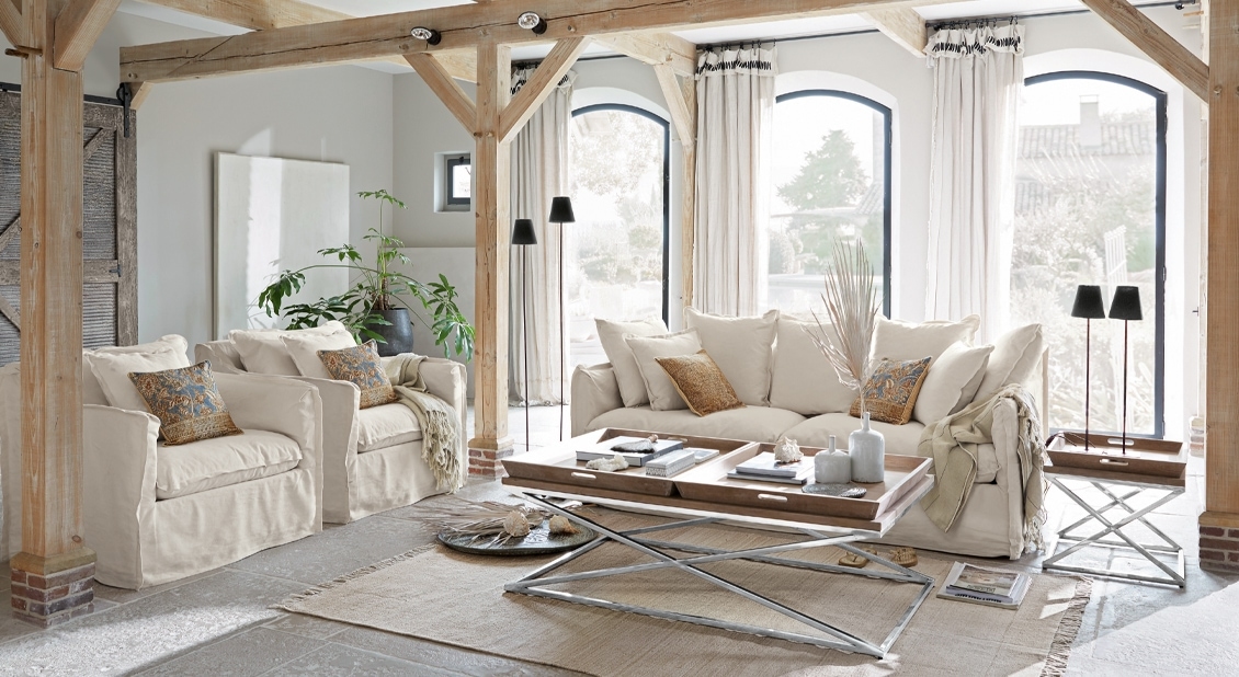 Gezellige woonkamer met beige stoffen bank en fauteuils, houten salontafel en natuurlijk licht