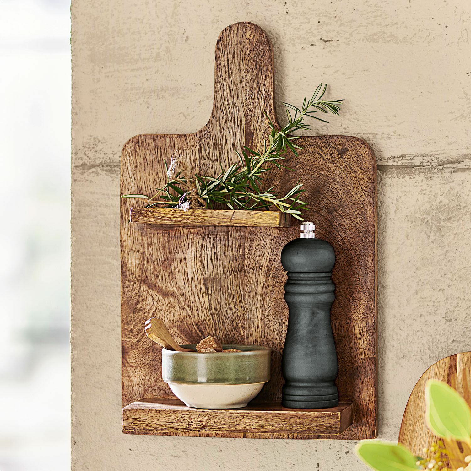 Houten snijplank met plankjes, groene takken en zwarte pepermolen, keukenwanddecoratie