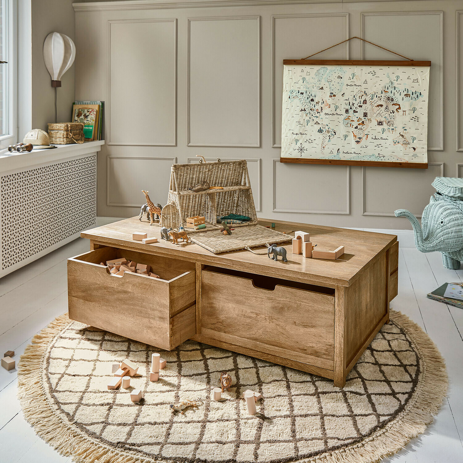 Houten speeltafel met lades en houten blokken op ronde vloerkleed in kinderkamer