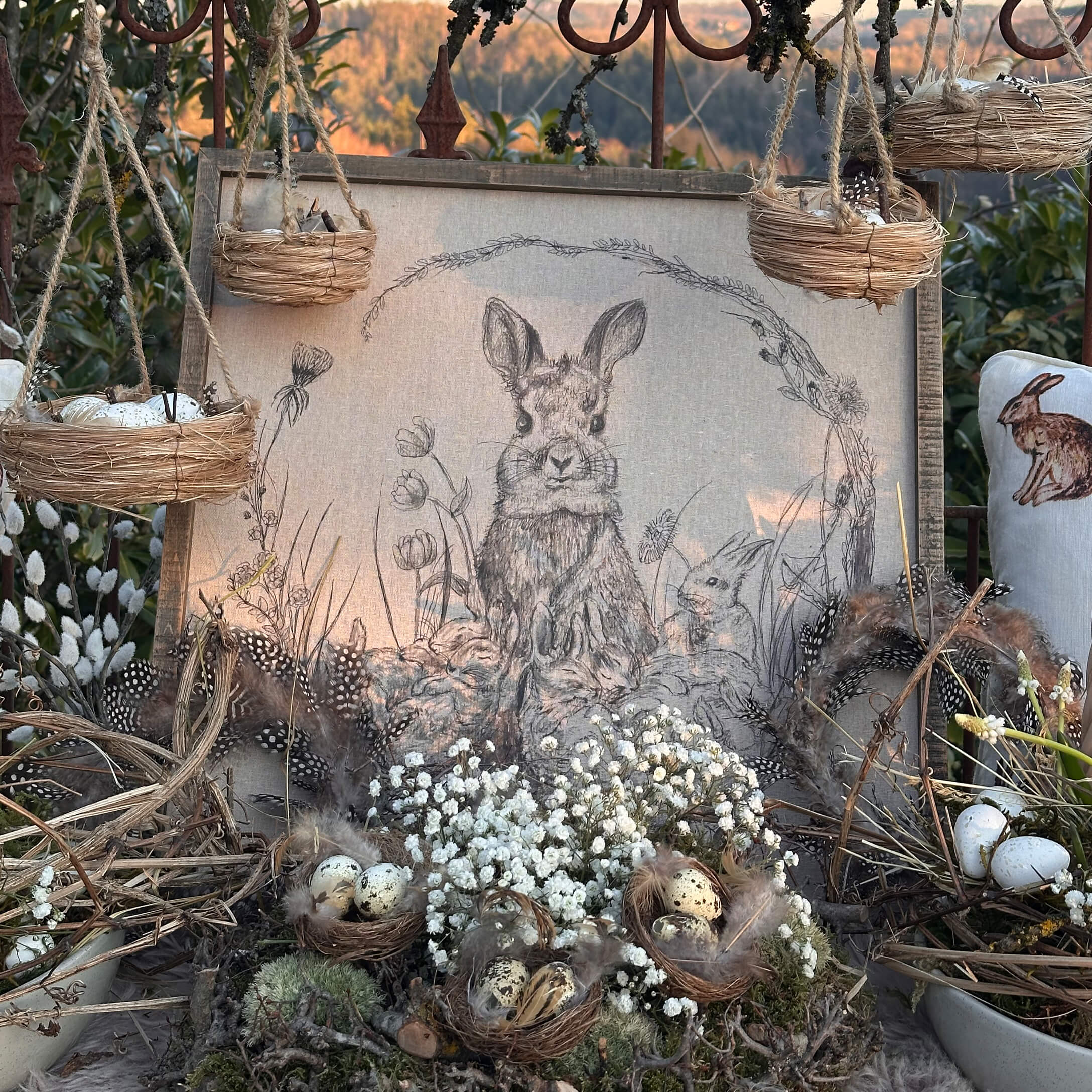 Natuurlijke paasdecoratie met nestjes, veren en konijnentekening op linnen doek