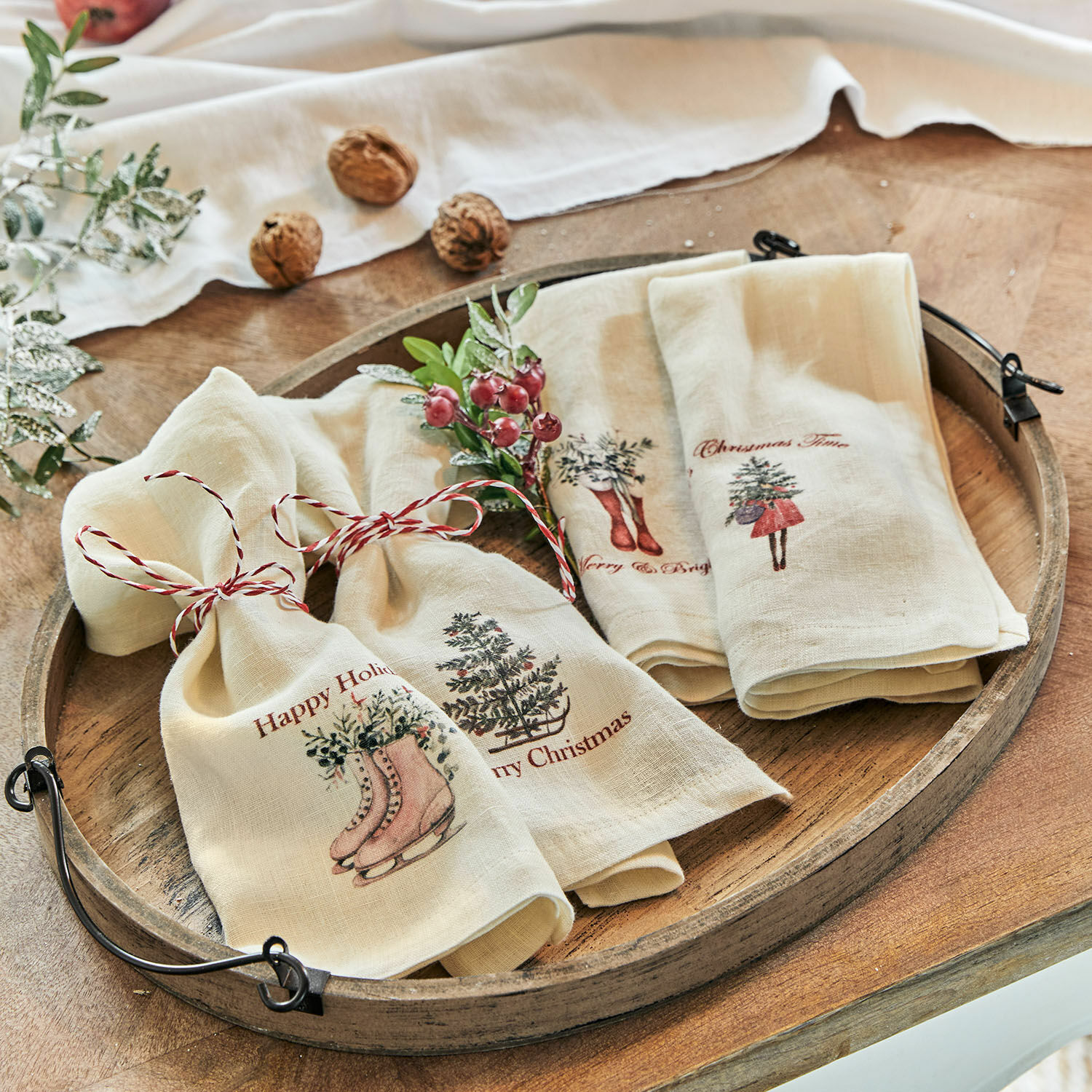 Crème linnen doeken met kerstmotieven en rood koord op rustieke houten schaal