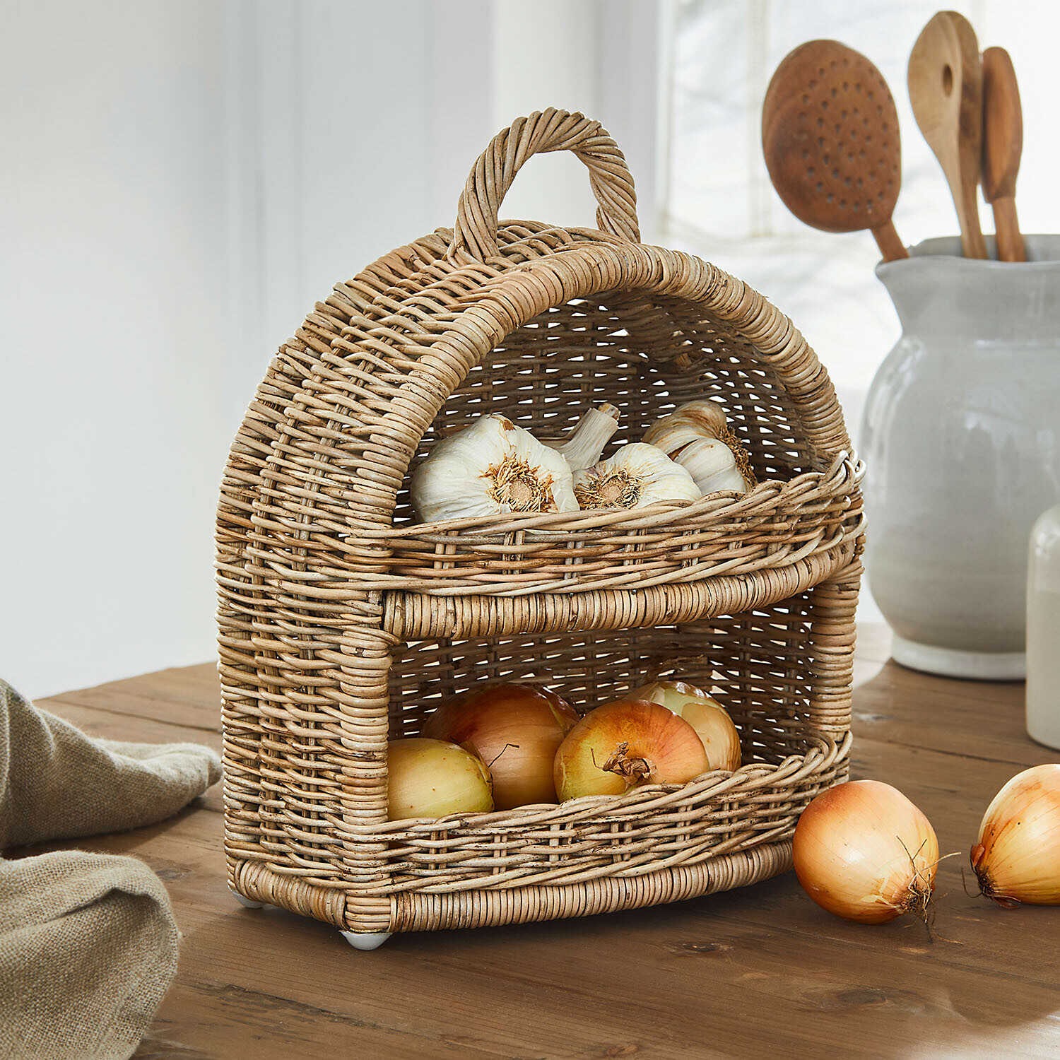 Tweedelige mand van natuurlijk riet met knoflook en uien op een rustieke houten tafel