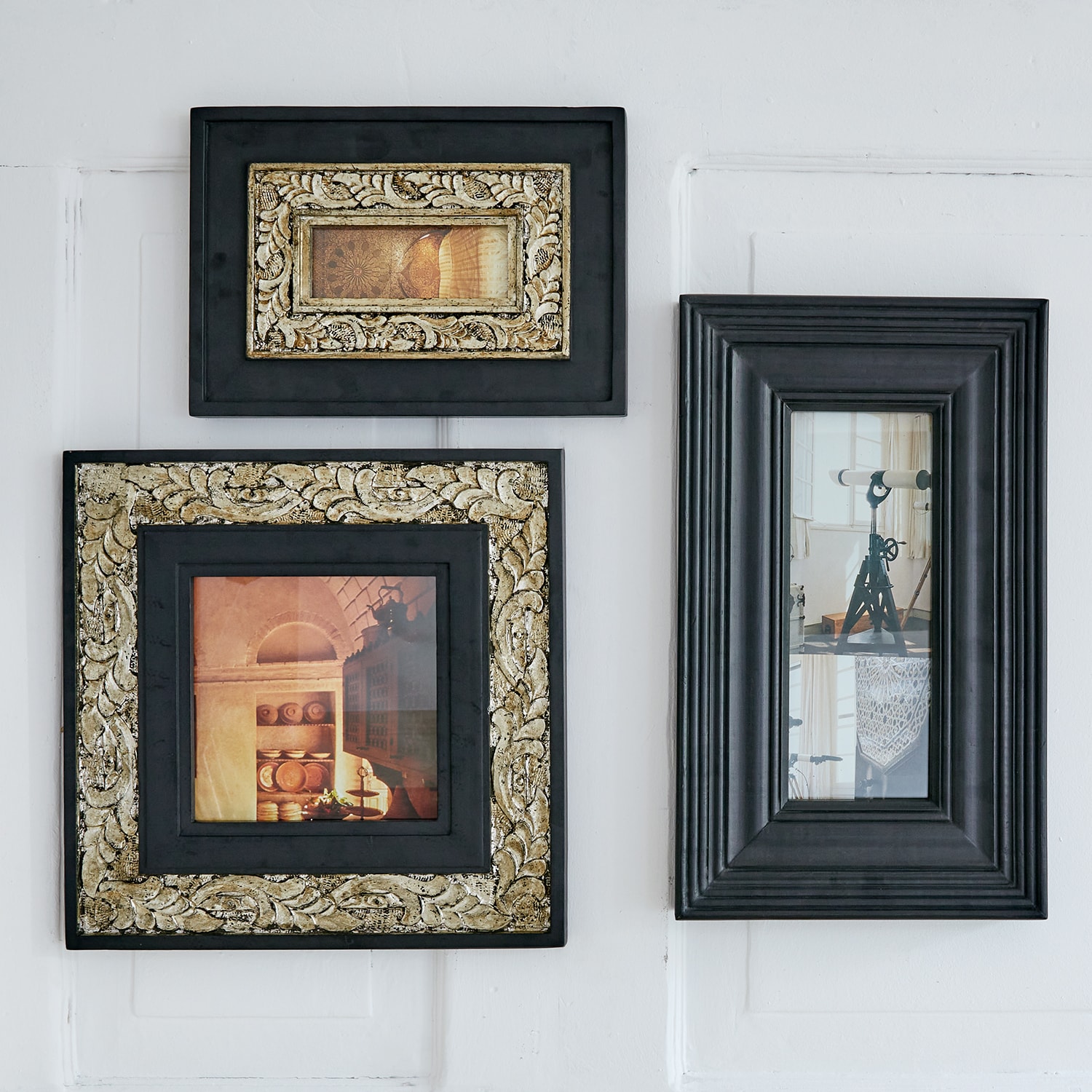 Set van drie zwarte lijsten met gouden details en vintage foto’s aan witte muur