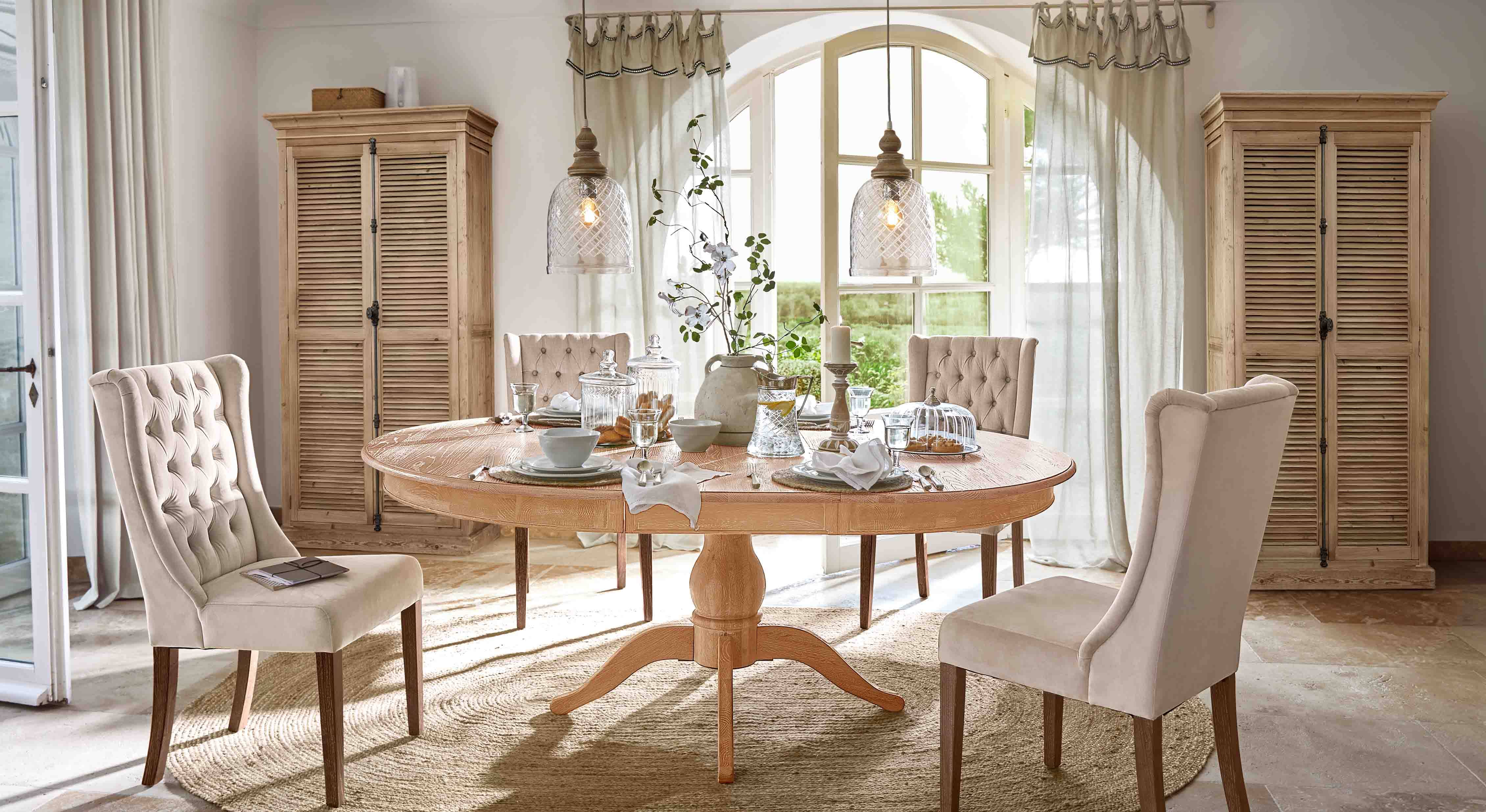 Eetkamer met ronde houten tafel en beige gestoffeerde stoelen in klassieke landelijke stijl