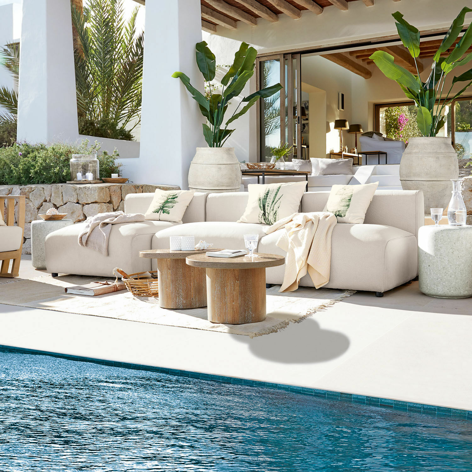 Modulaire bank Vézère Beige stoffen bank op terras bij zwembad met houten tafels en decoratieve kussens