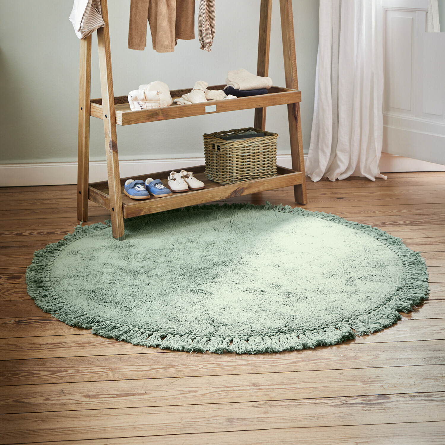 Ronde zachte groene vloerkleed met franjes op houten vloer in kinderkamer
