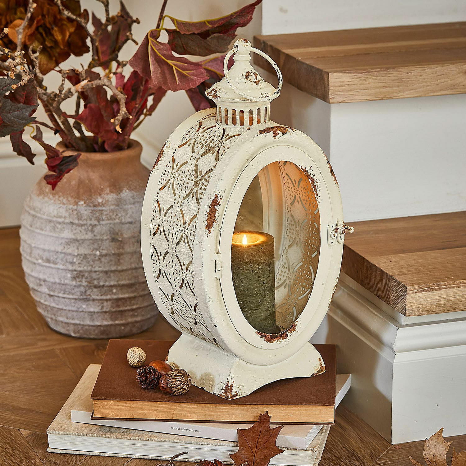 Lantaarn Sublimelle Vintage metalen lantaarn in crème met brandende kaars en herfstdecoratie op boeken