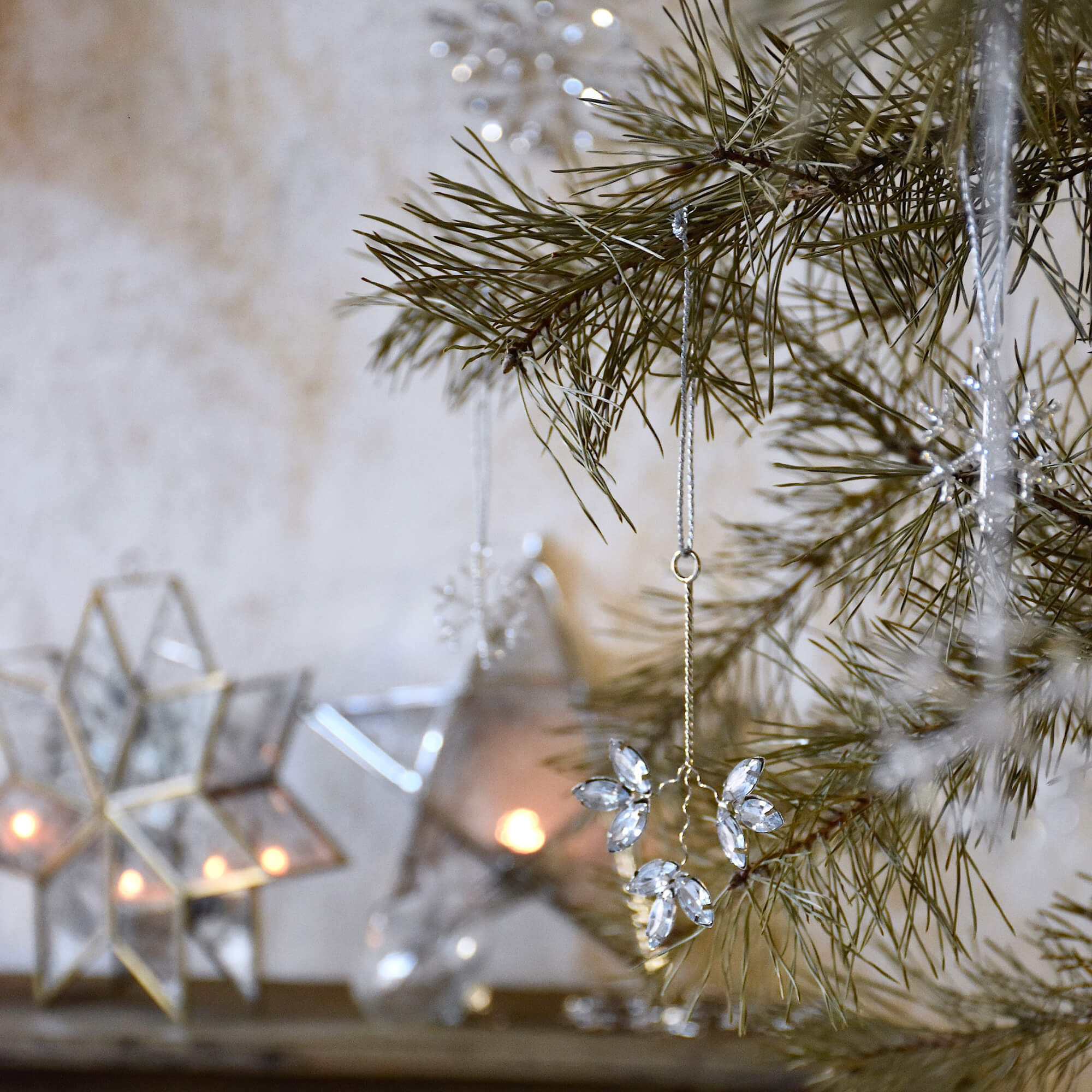 Kerstdecoratie van transparante kristallen aan dennen tak met lantaarns op de achtergrond
