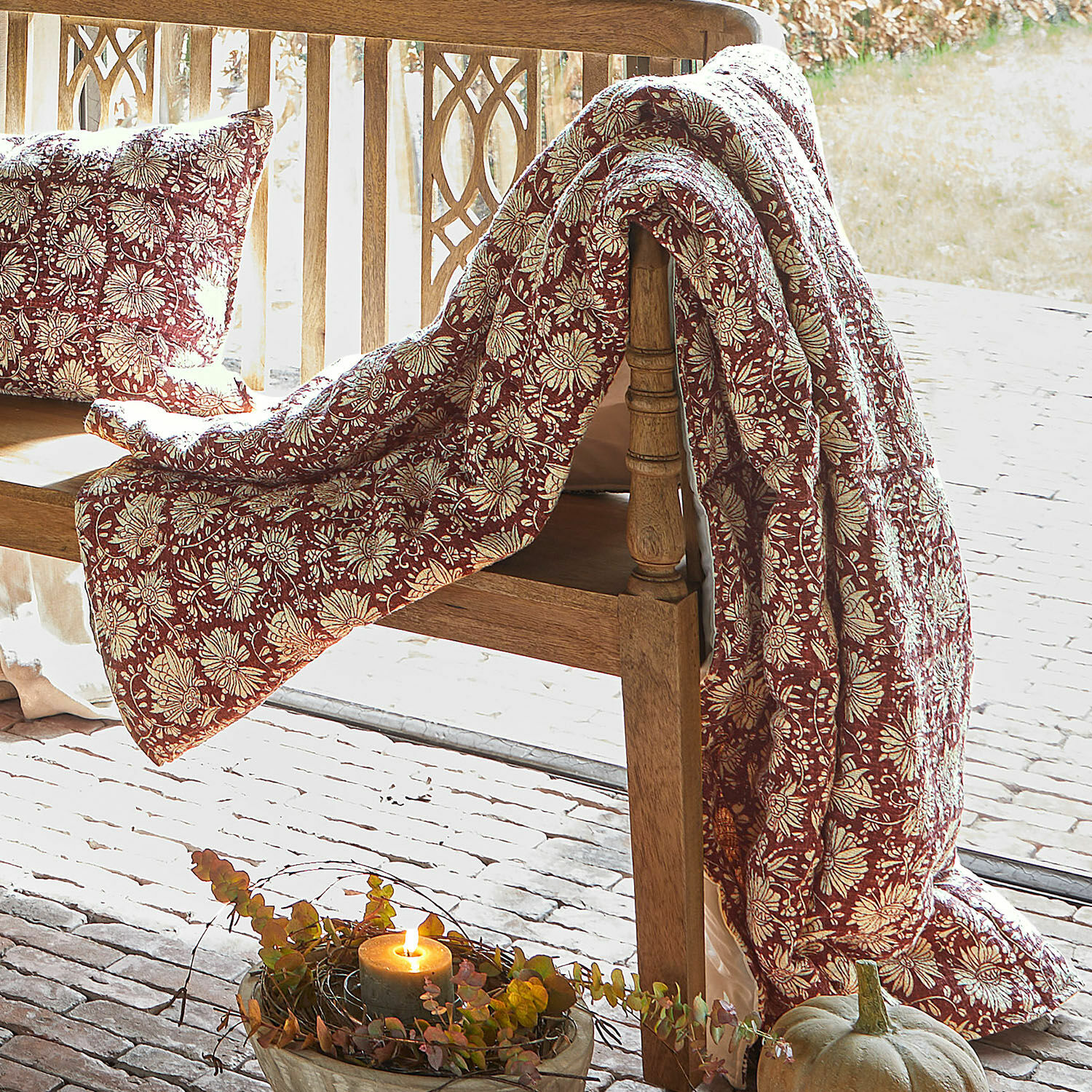 Plaid Soleique Rode deken en kussen met bloemenpatroon op houten bank, herfstdecoratie met pompoen en kaars